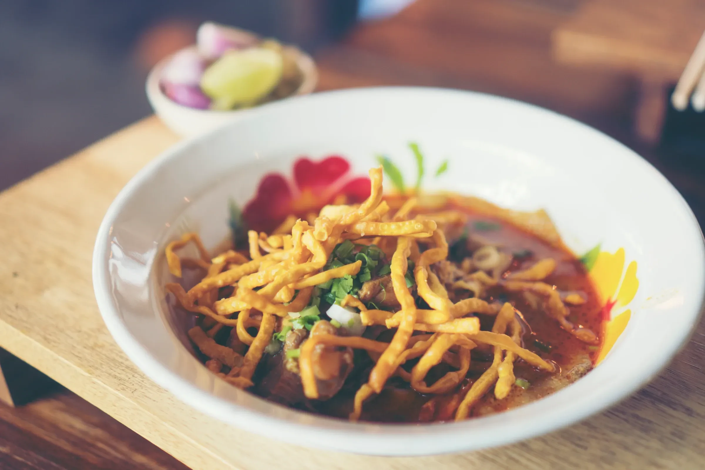 A bowl of khao soi, northern Thai curry noodle soup topped with crispy fried noodles