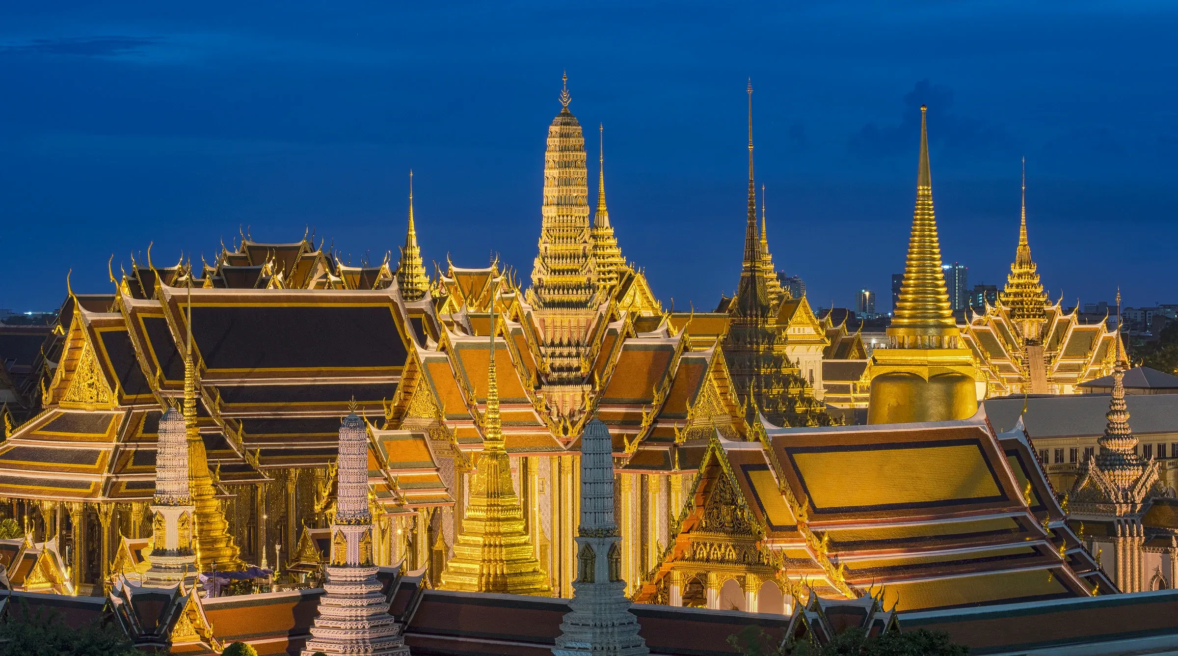 The golden roofs and spires of the Temple of the Emerald Buddha in Bangkok at dusk