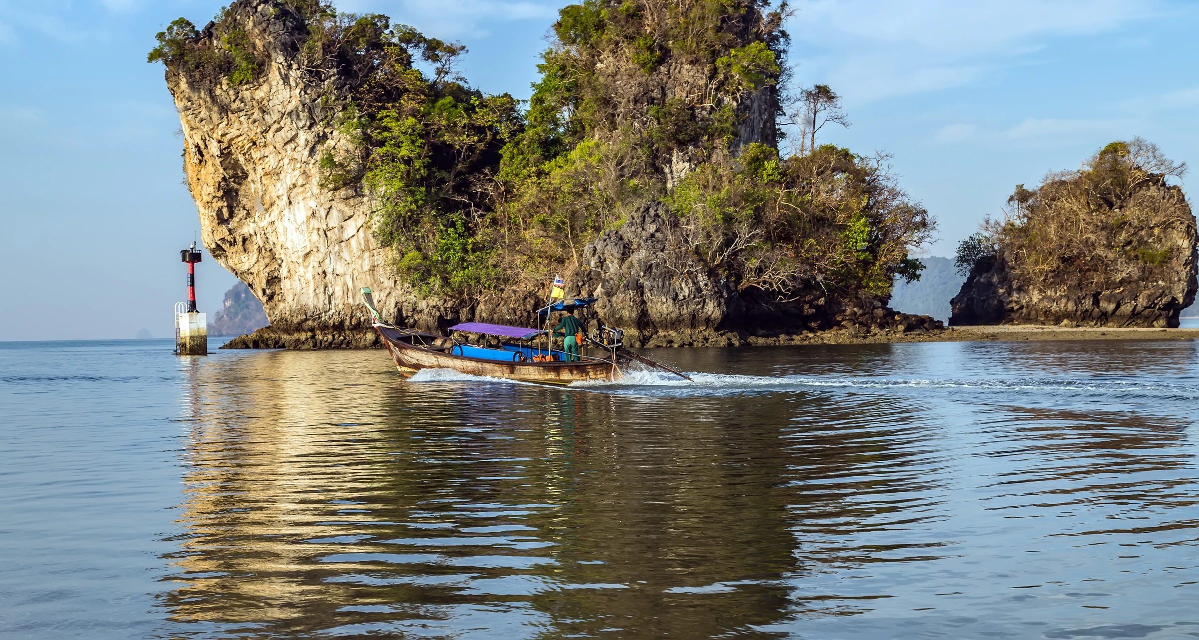 A traditional longtail boat beside limestone karst cliffs in Krabi, Thailand