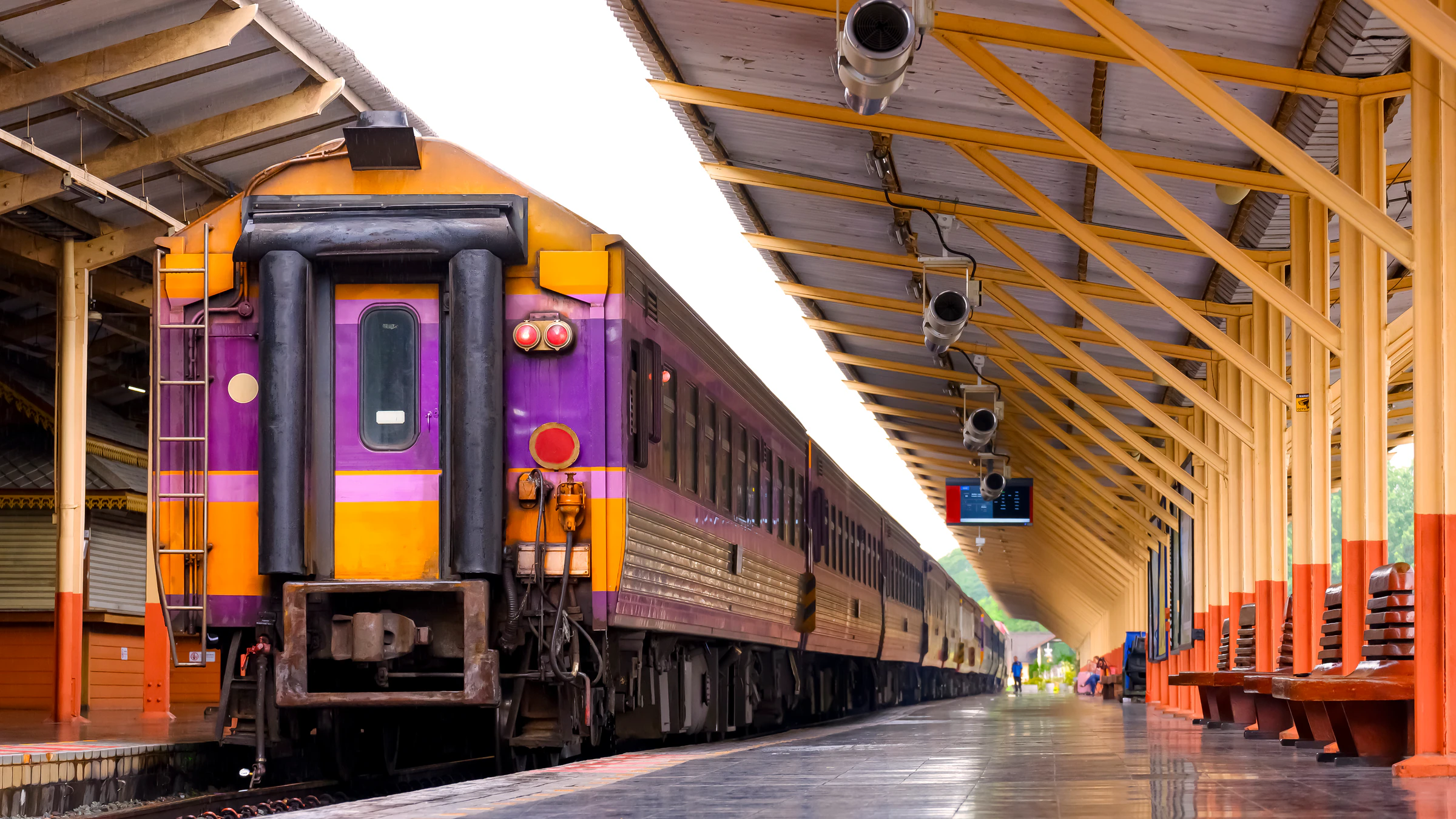 A purple and yellow passenger train standing at a station platform