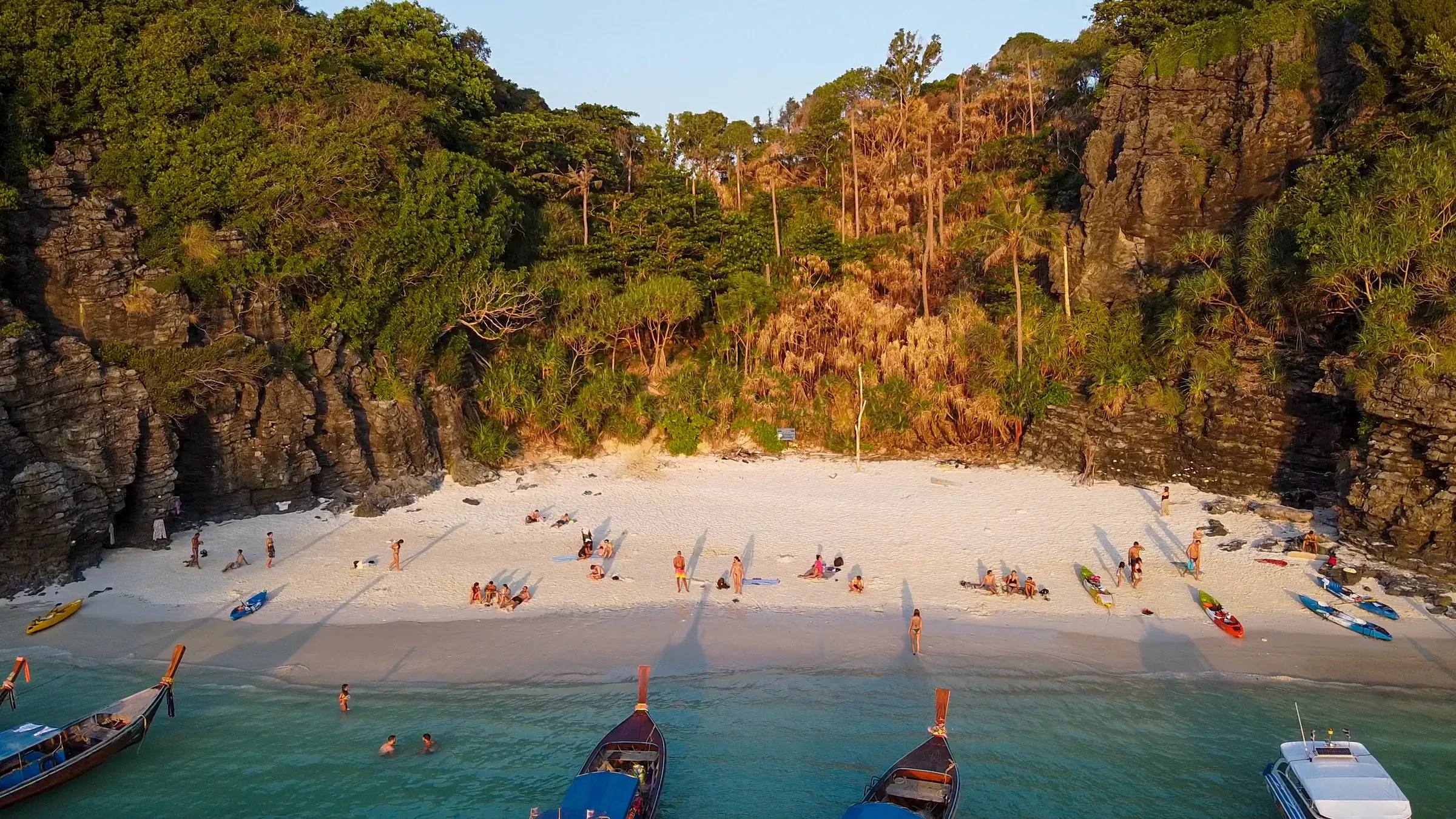 A small white-sand cove on Koh Phi Phi Don with longtail boats pulled up