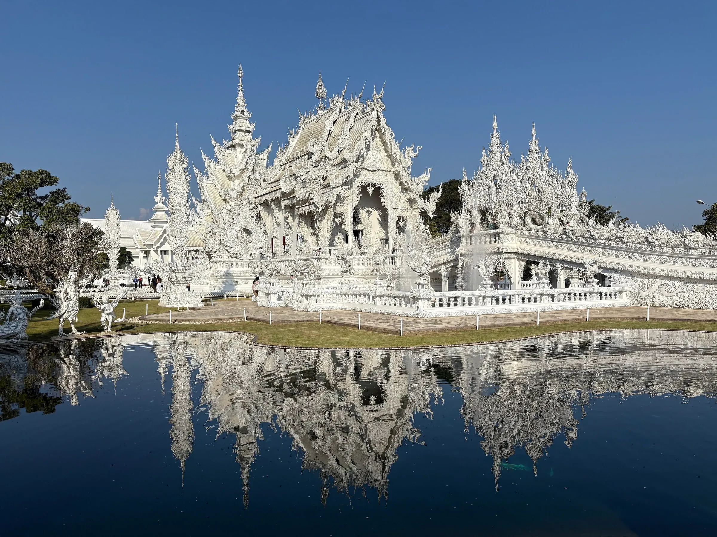 The white temple of Wat Rong Khun in Chiang Rai reflected in a still pool