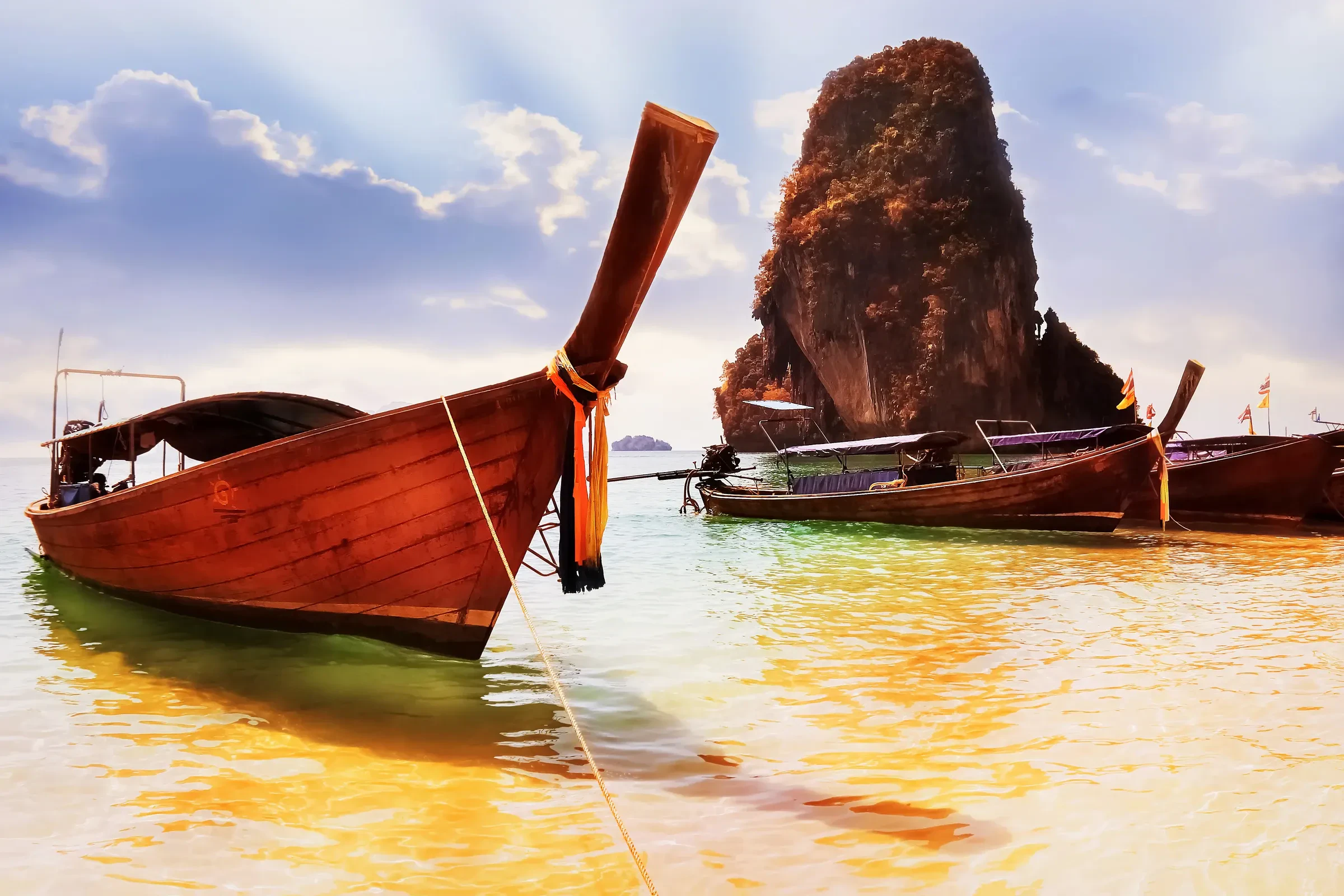 Longtail boats on Railay beach with a limestone tower rising behind them