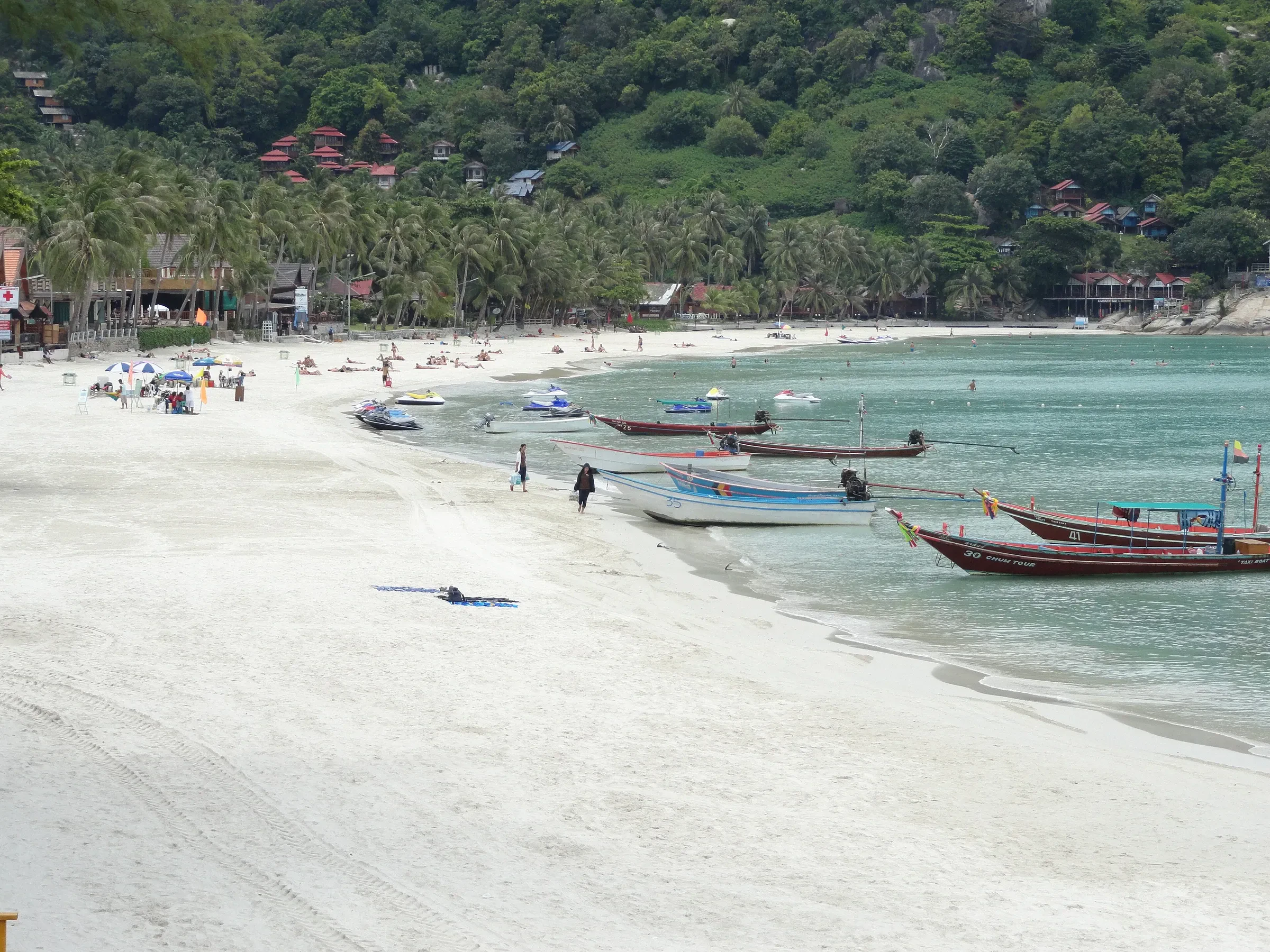 Haad Rin Sunrise Beach on Koh Phangan in daylight, with long-tail boats along the shore
