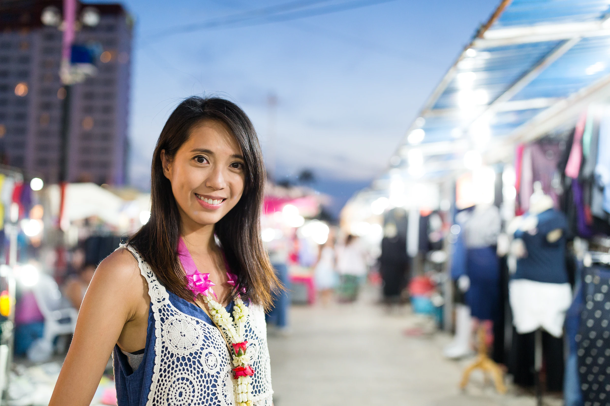 A smiling woman standing in a night market in Thailand