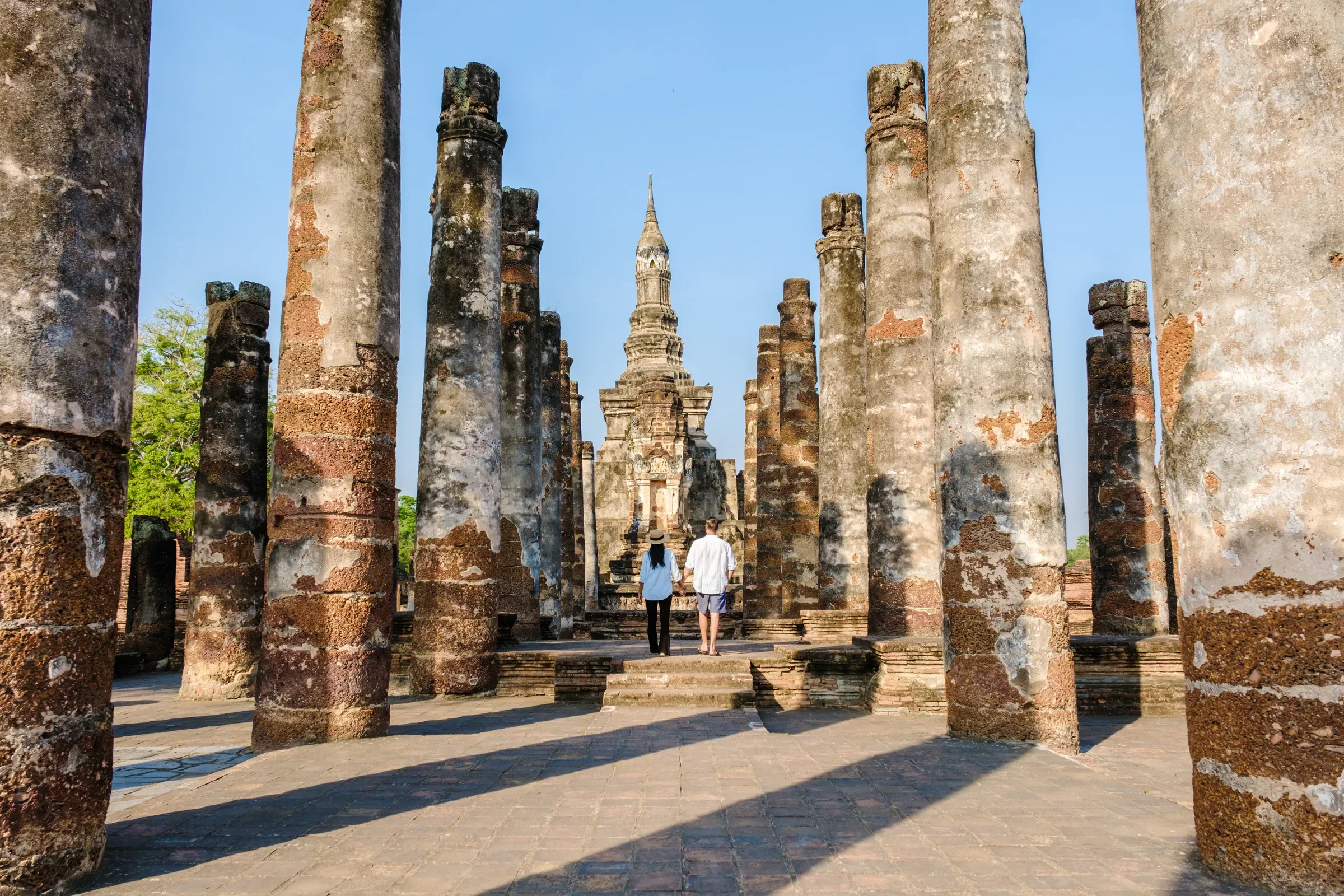 Visitors among old columns at Wat Mahathat in Sukhothai Historical Park