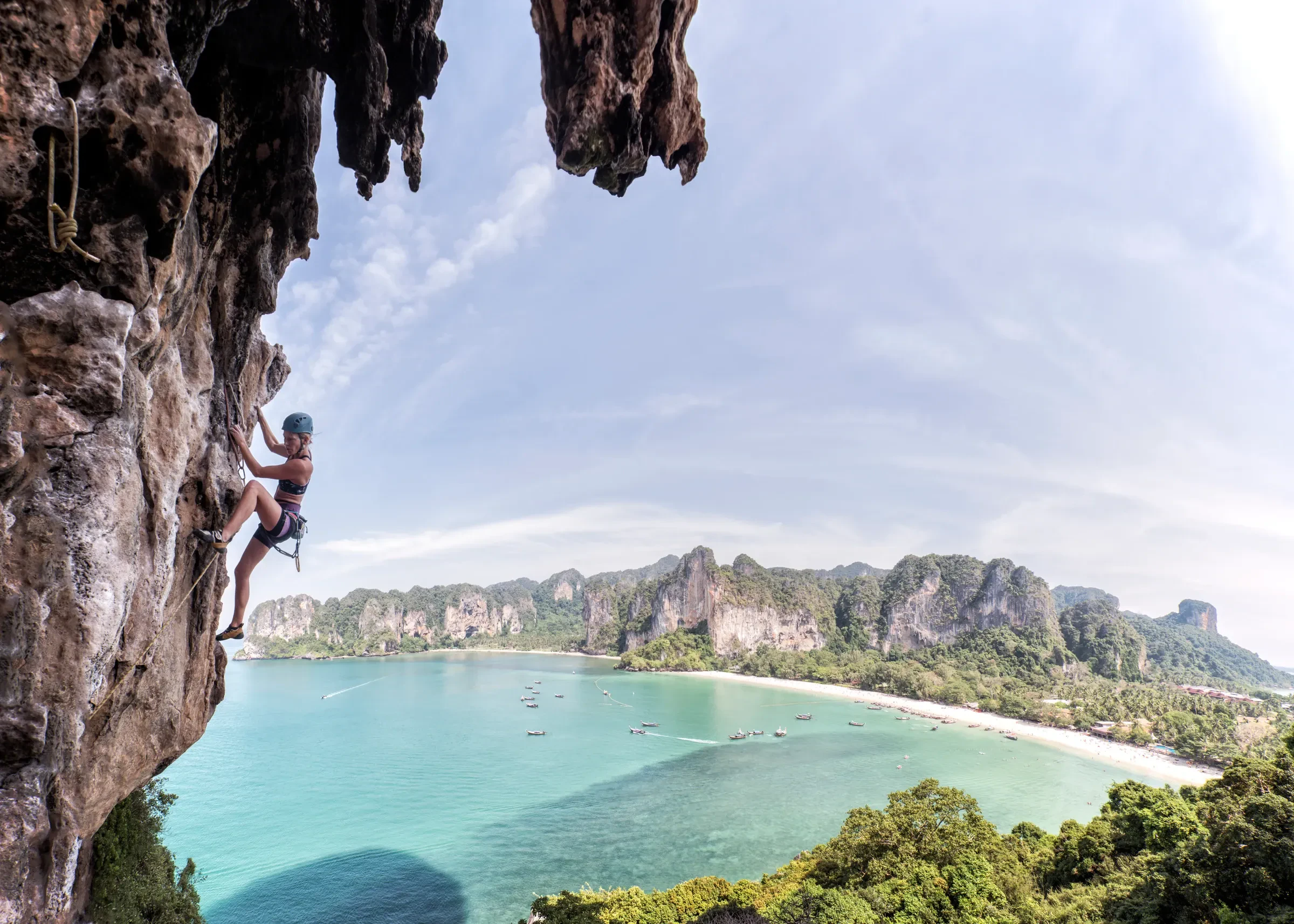 A climber on a limestone wall above the bay at Railay