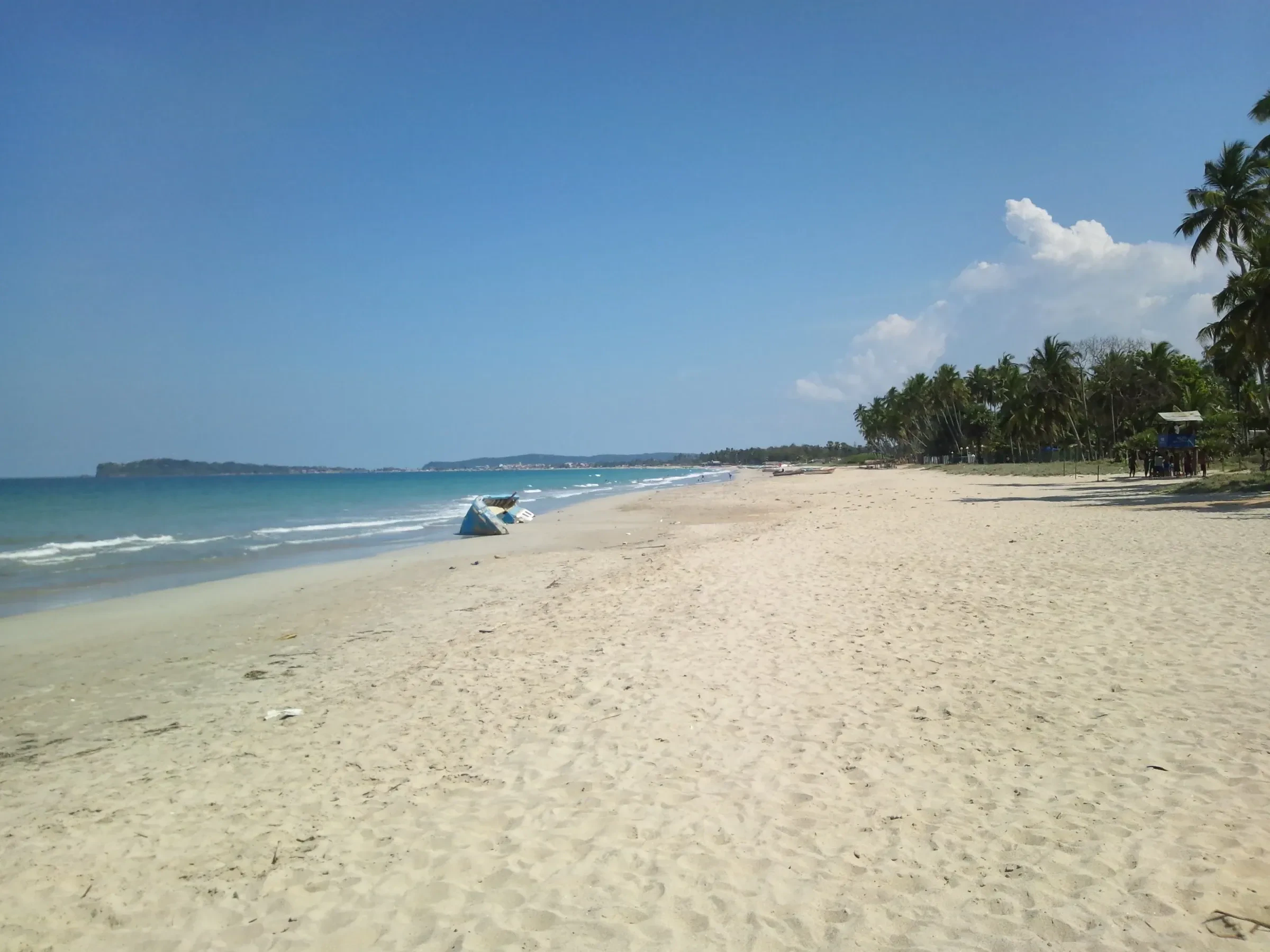 A long stretch of pale sand and palm trees at Uppuveli beach near Trincomalee