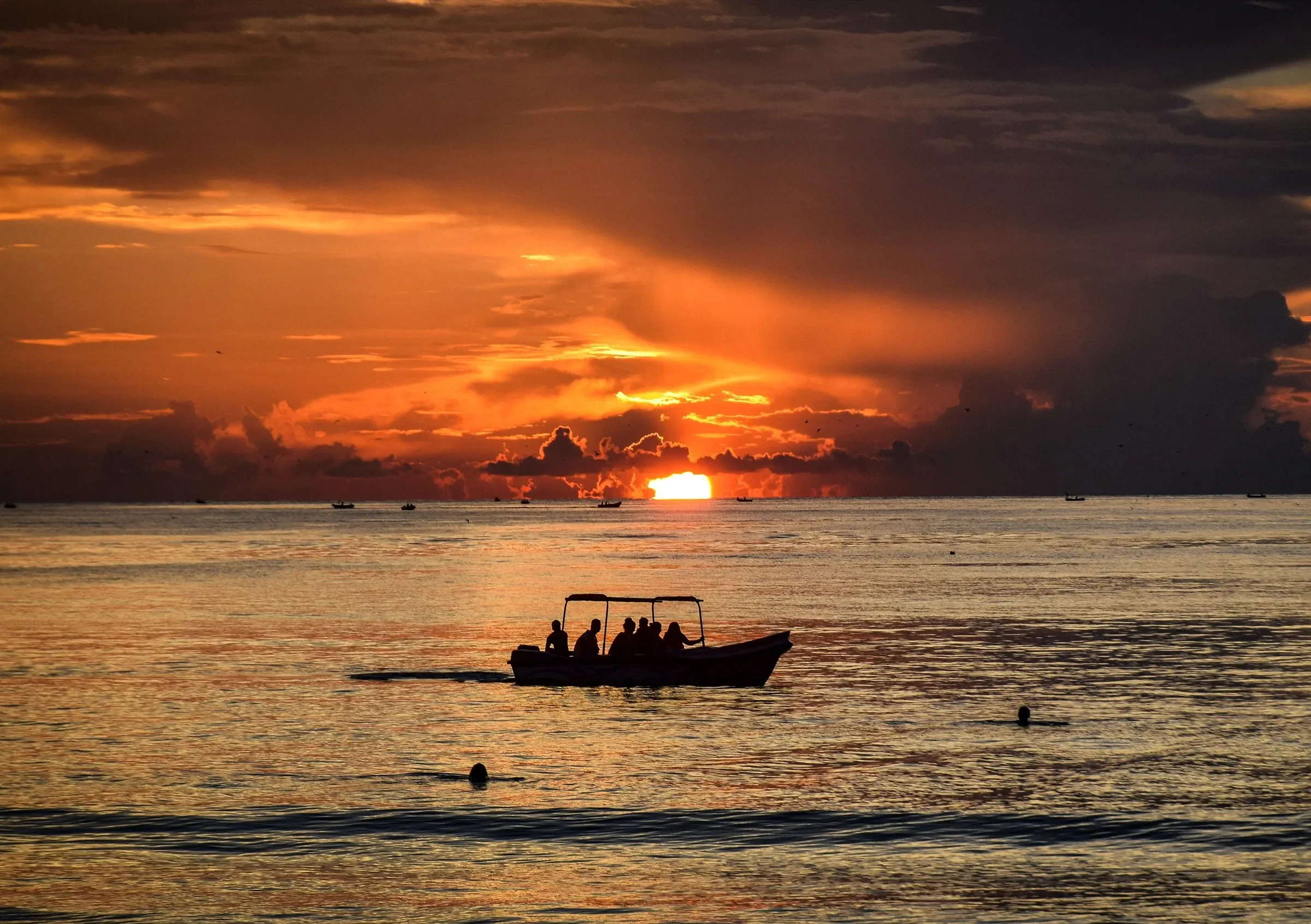 A small boat on the sea at sunrise off Trincomalee, with orange clouds above the horizon