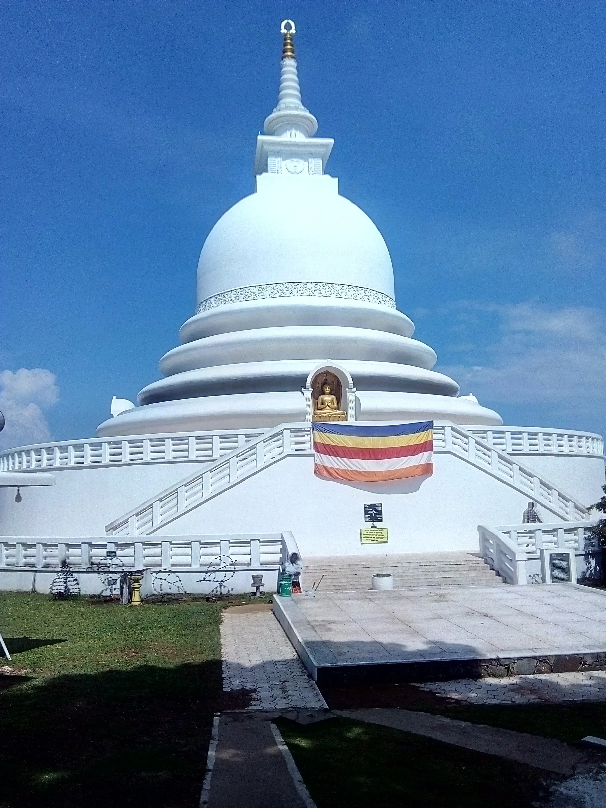The white dome of the Japanese Peace Pagoda on Rumassala, seen from the front steps against a blue sky