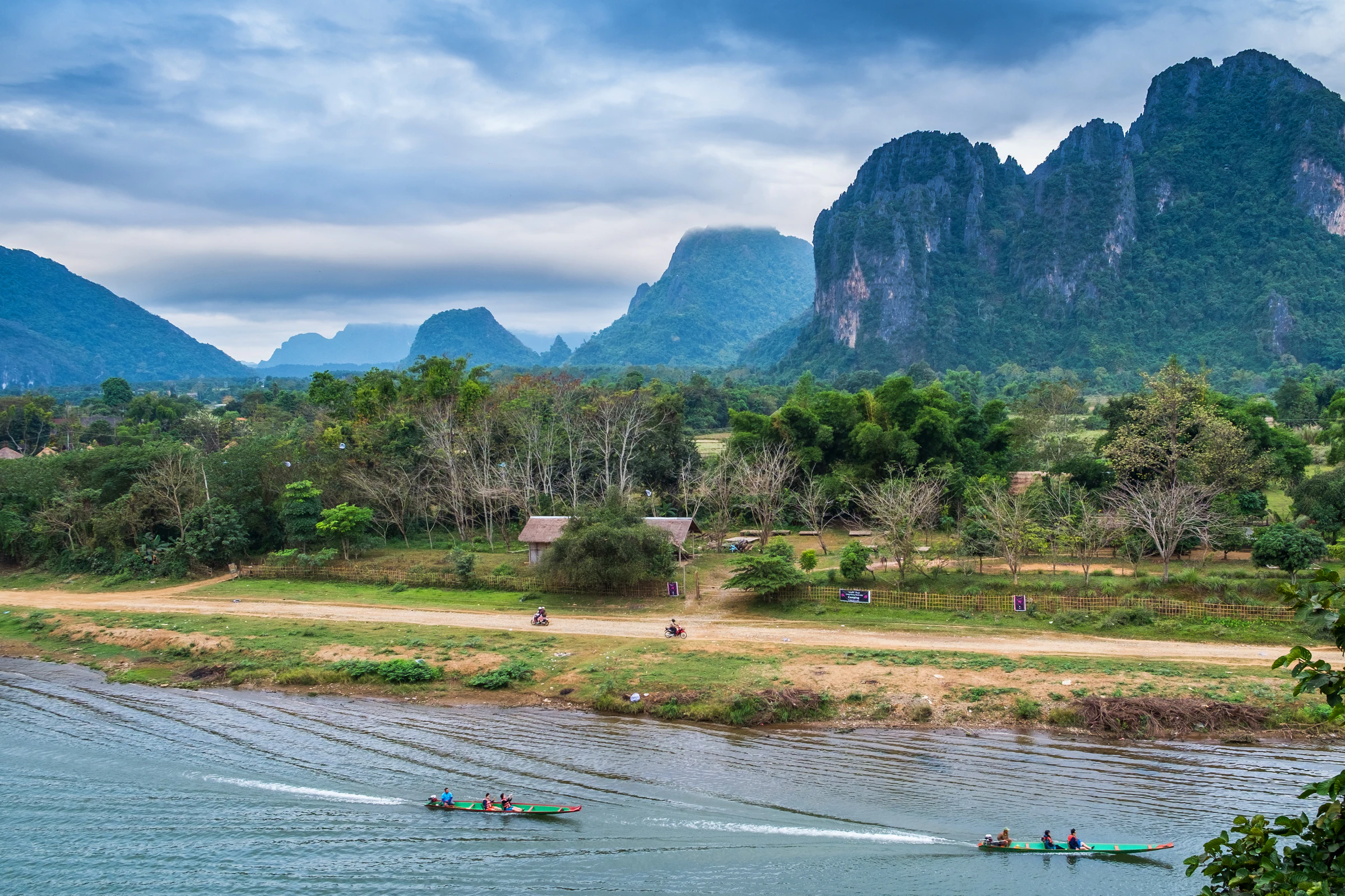 Limestone peaks rising behind the Nam Song river at Vang Vieng, with longtail boats on the bank