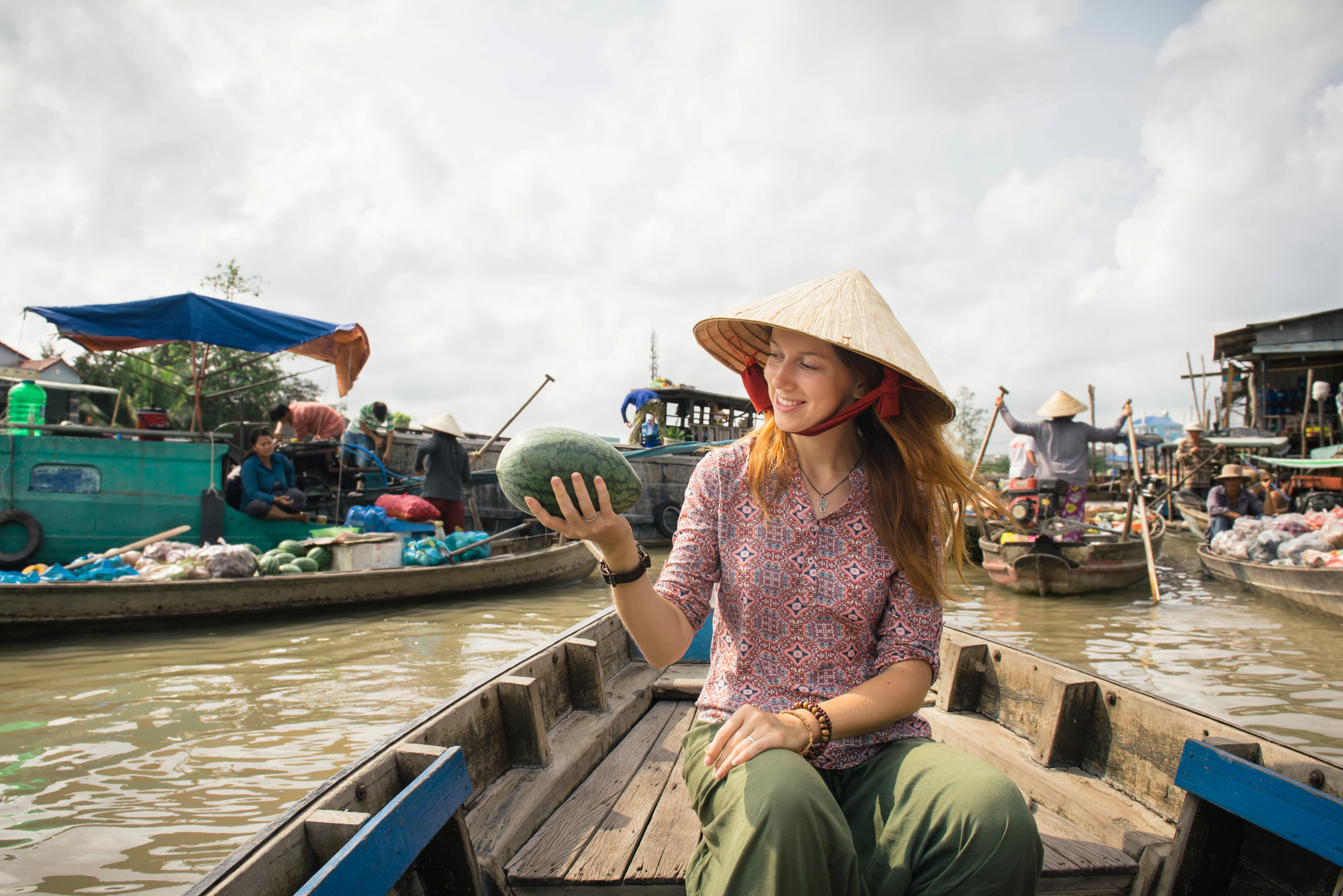 A traveller buying fruit from a boat at the Cai Rang floating market