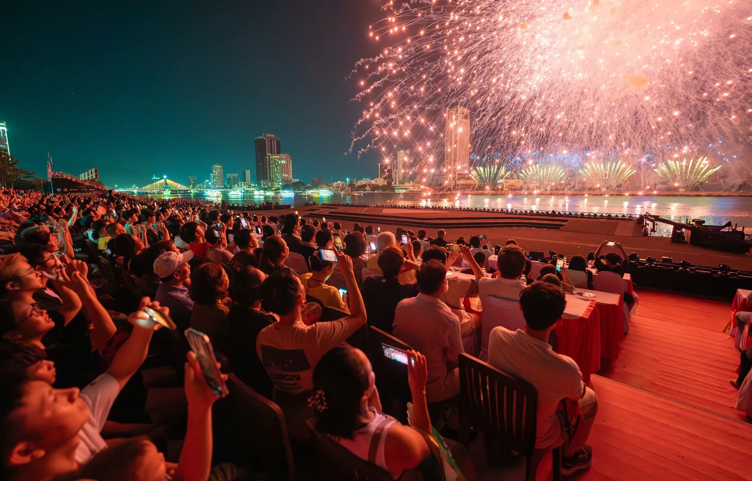 Spectators seated in a grandstand along the Han River watching fireworks at the Da Nang International Fireworks Festival
