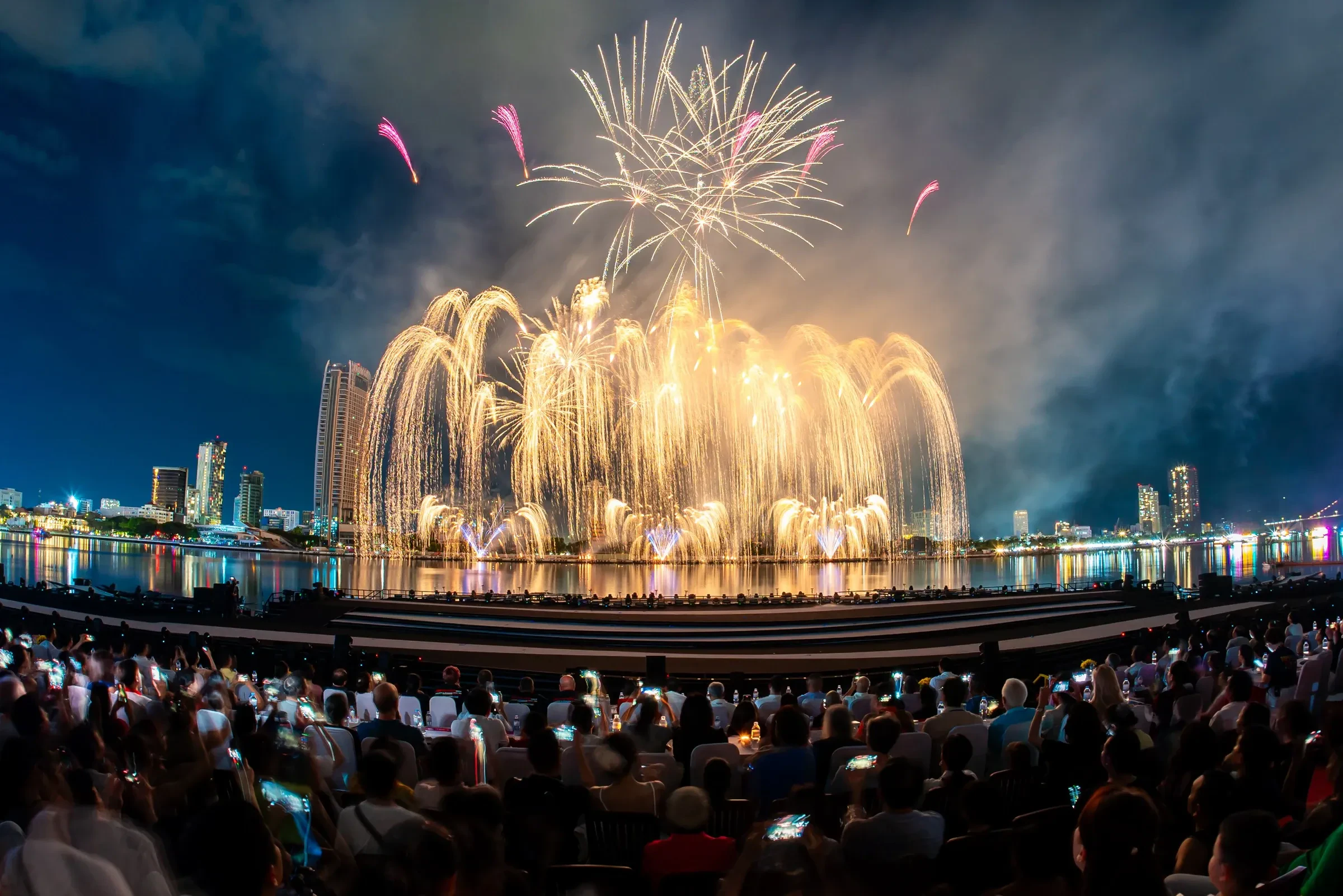 Fireworks bursting over the Han River while a crowd watches from the riverside in Da Nang