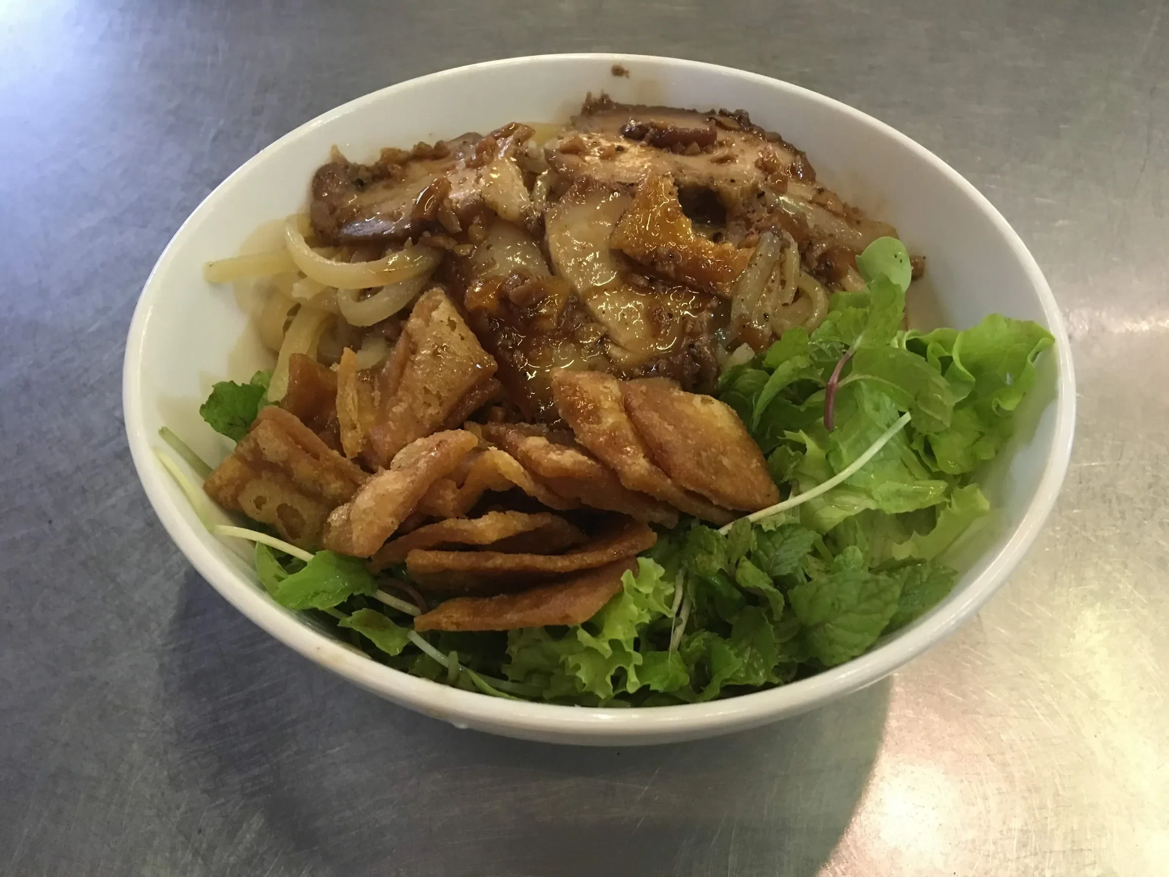 A bowl of cao lau with pork and crisp noodle pieces in Hoi An