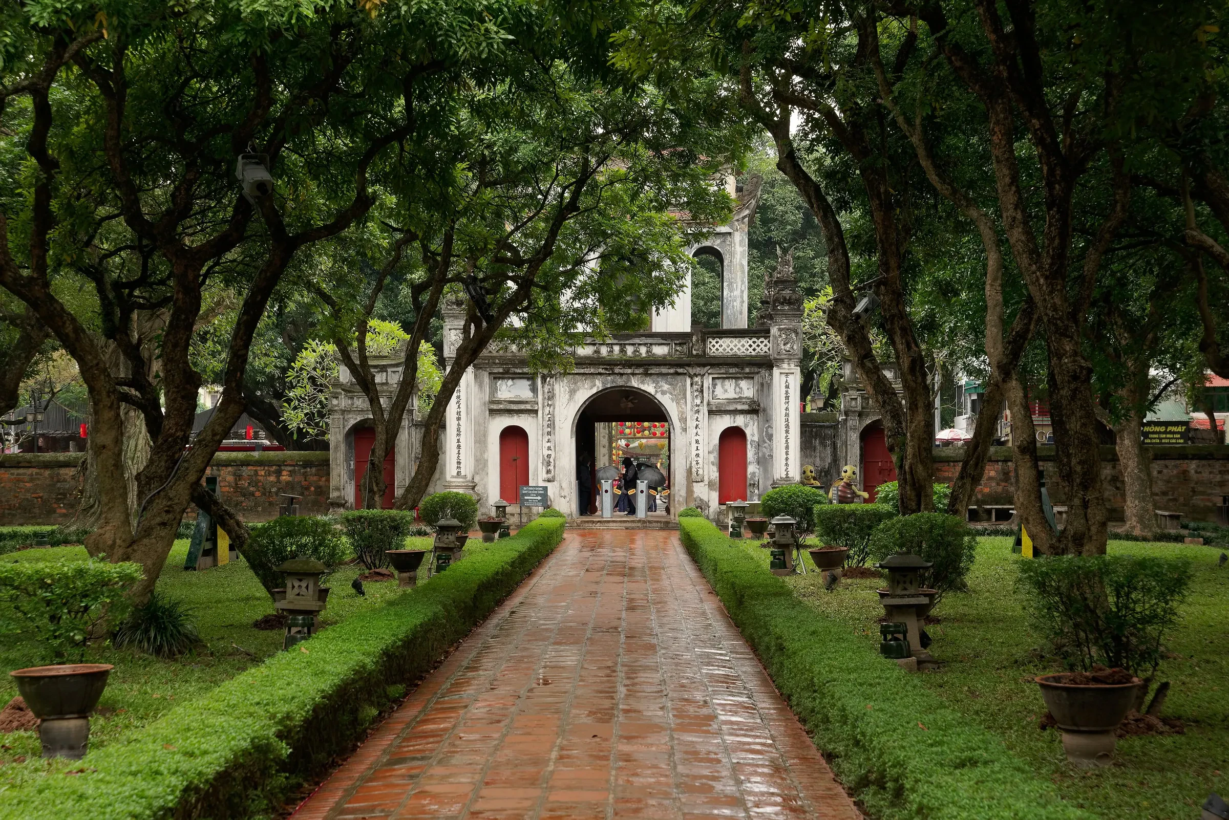 The main gate of the Temple of Literature in Hanoi, seen along a paved path between hedges
