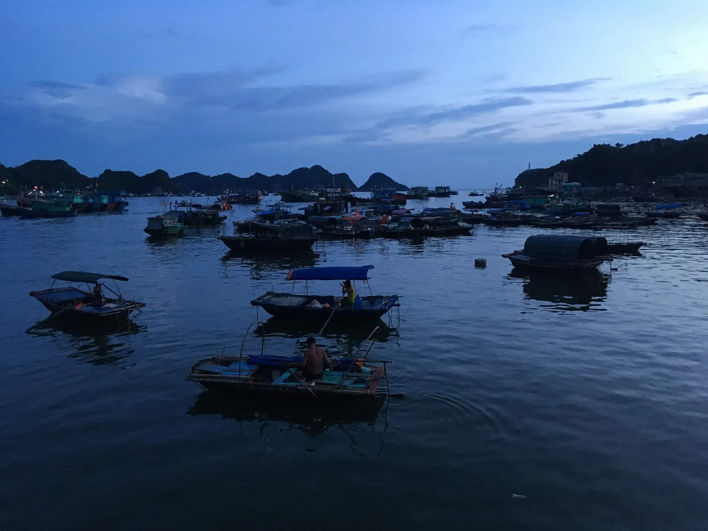 Small boats moored in the harbour at Cat Ba Town at dusk