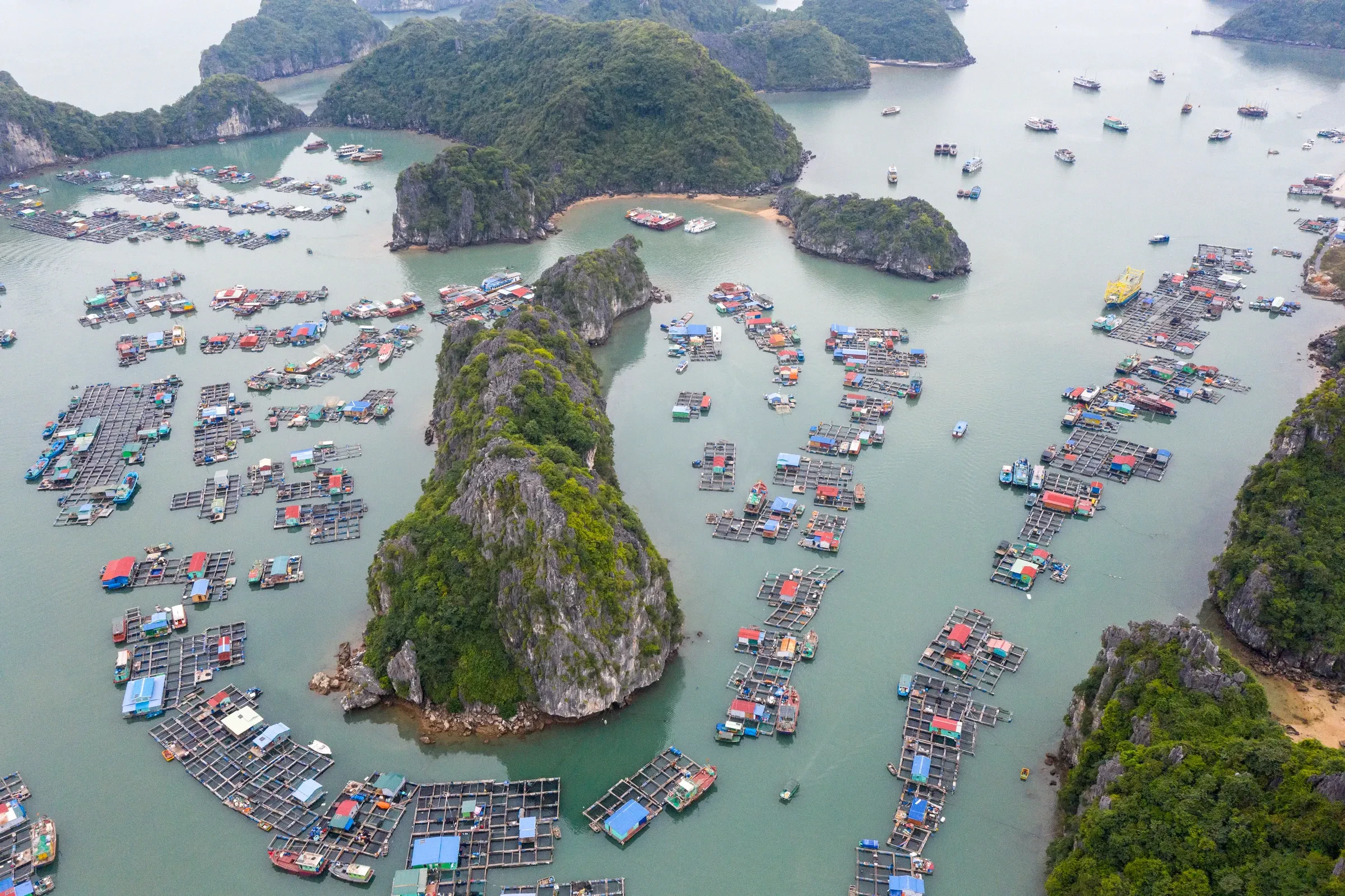 Aerial view of a floating fishing village among limestone islands in Lan Ha Bay