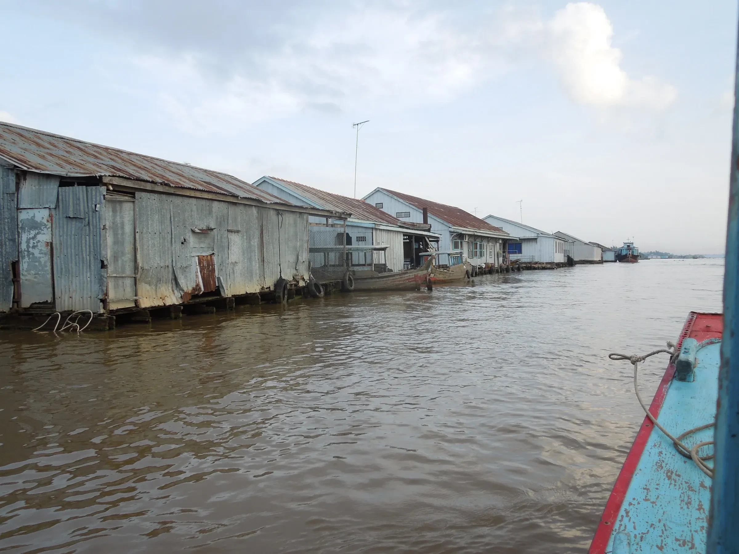 Floating houses moored in a row on the river at Chau Doc