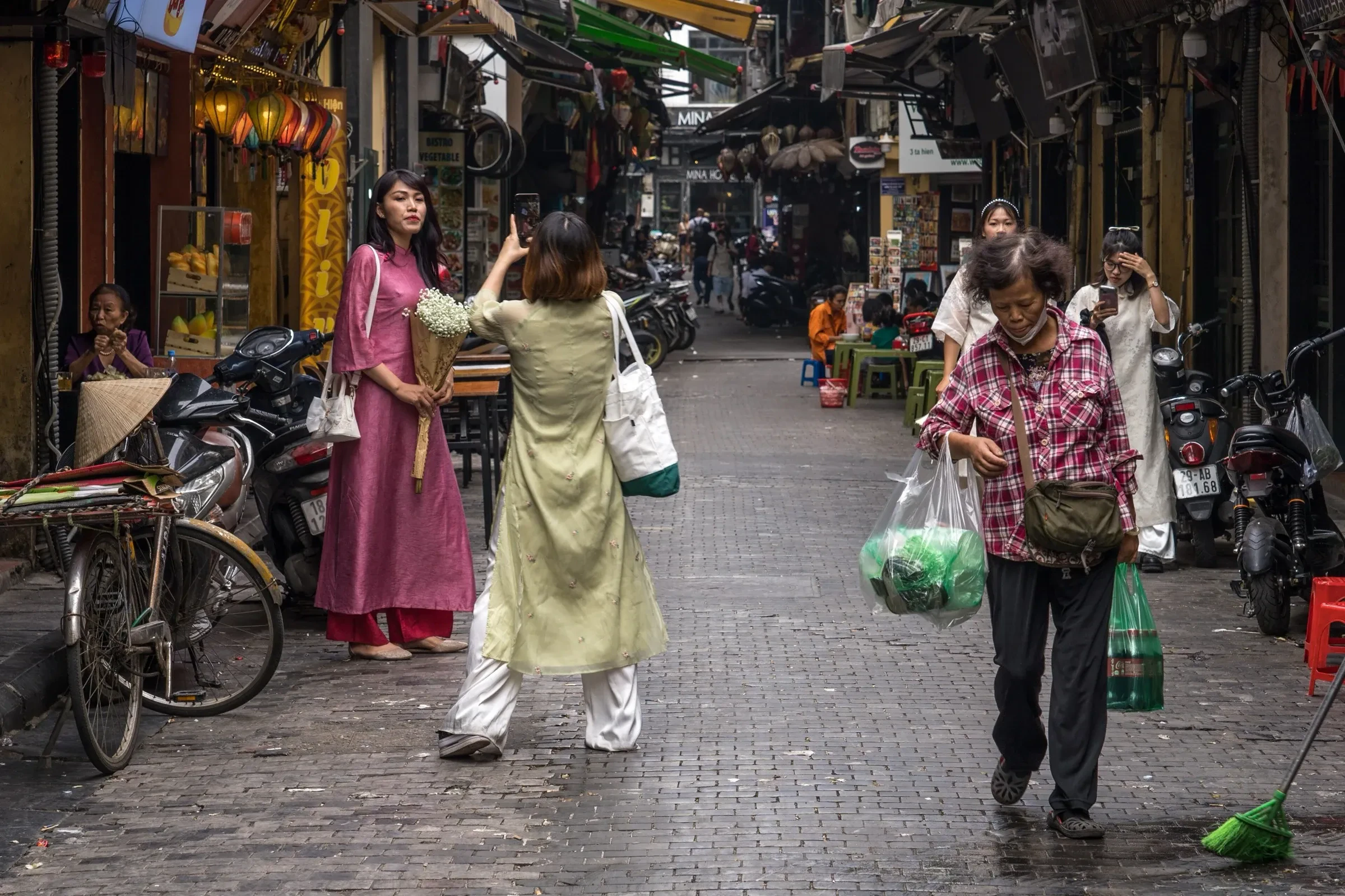 People walking along a narrow lane in Hanoi's Old Quarter