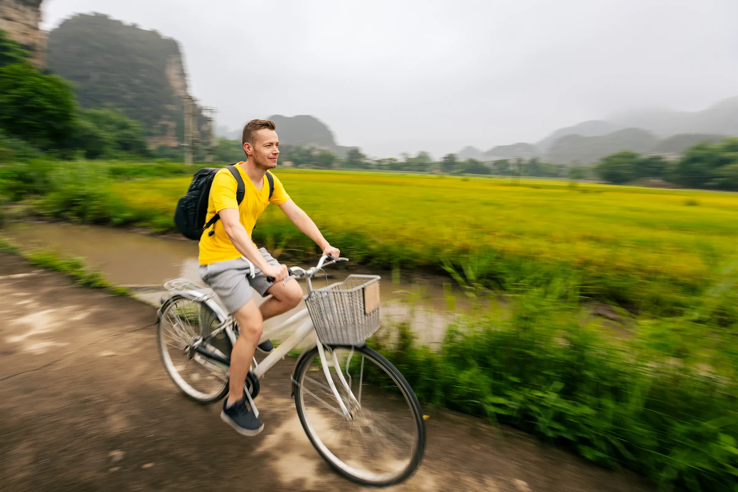 A cyclist riding between rice fields and limestone karsts in Ninh Binh, Vietnam