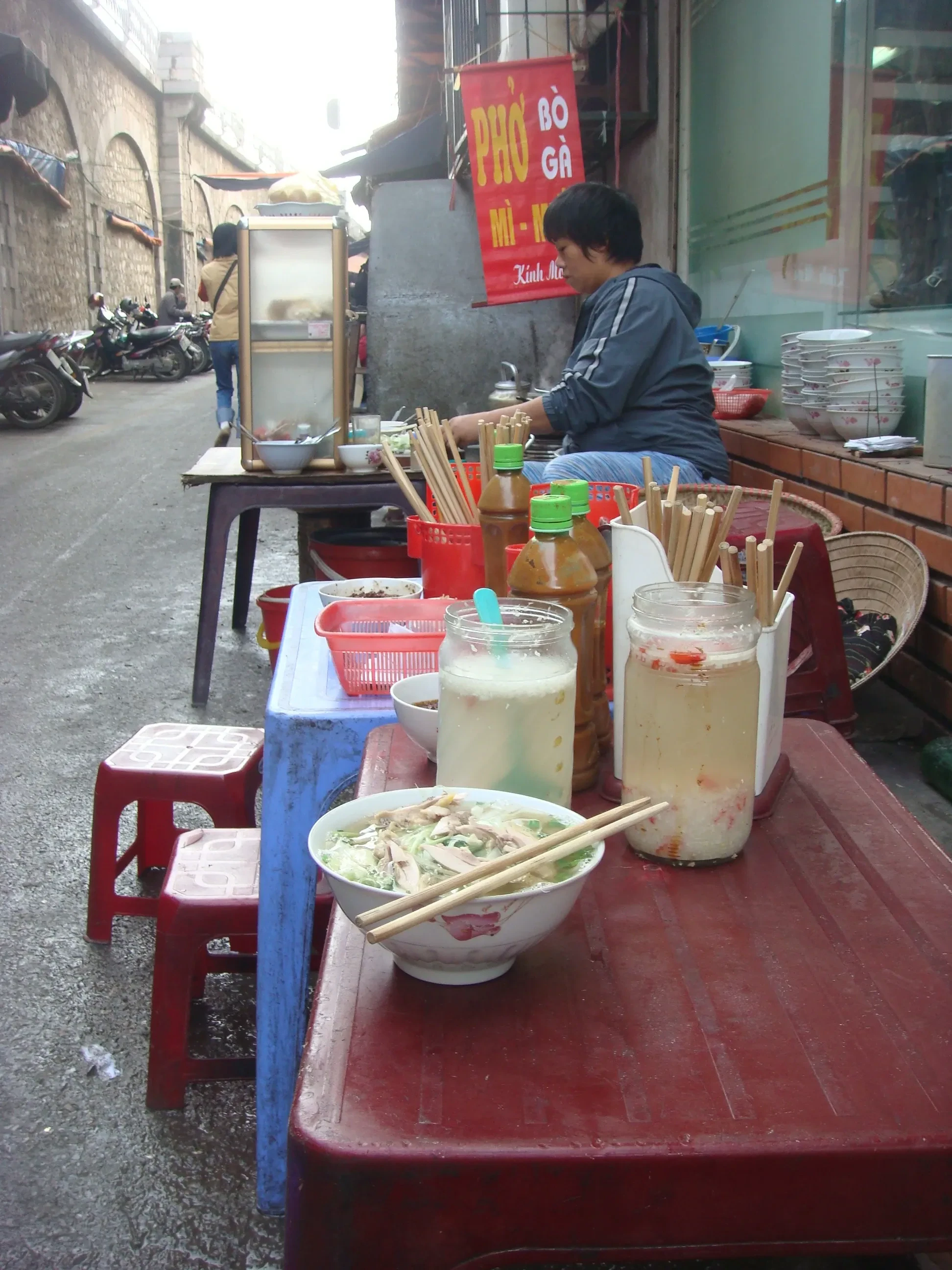 A street vendor's pho stall with plastic stools on a Hanoi pavement