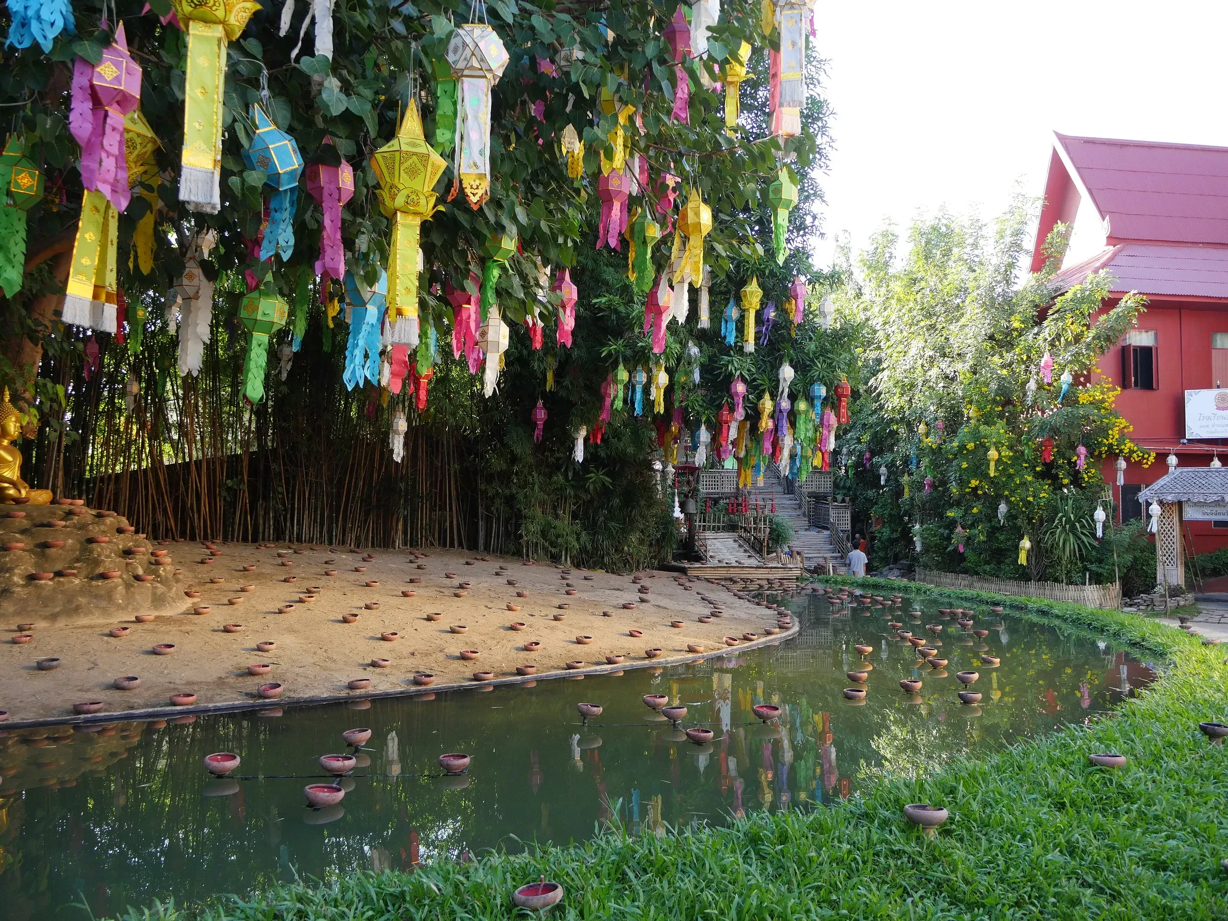 Colourful Lanna lanterns hanging from trees over the pond at Wat Phan Tao in Chiang Mai during Loi Krathong season
