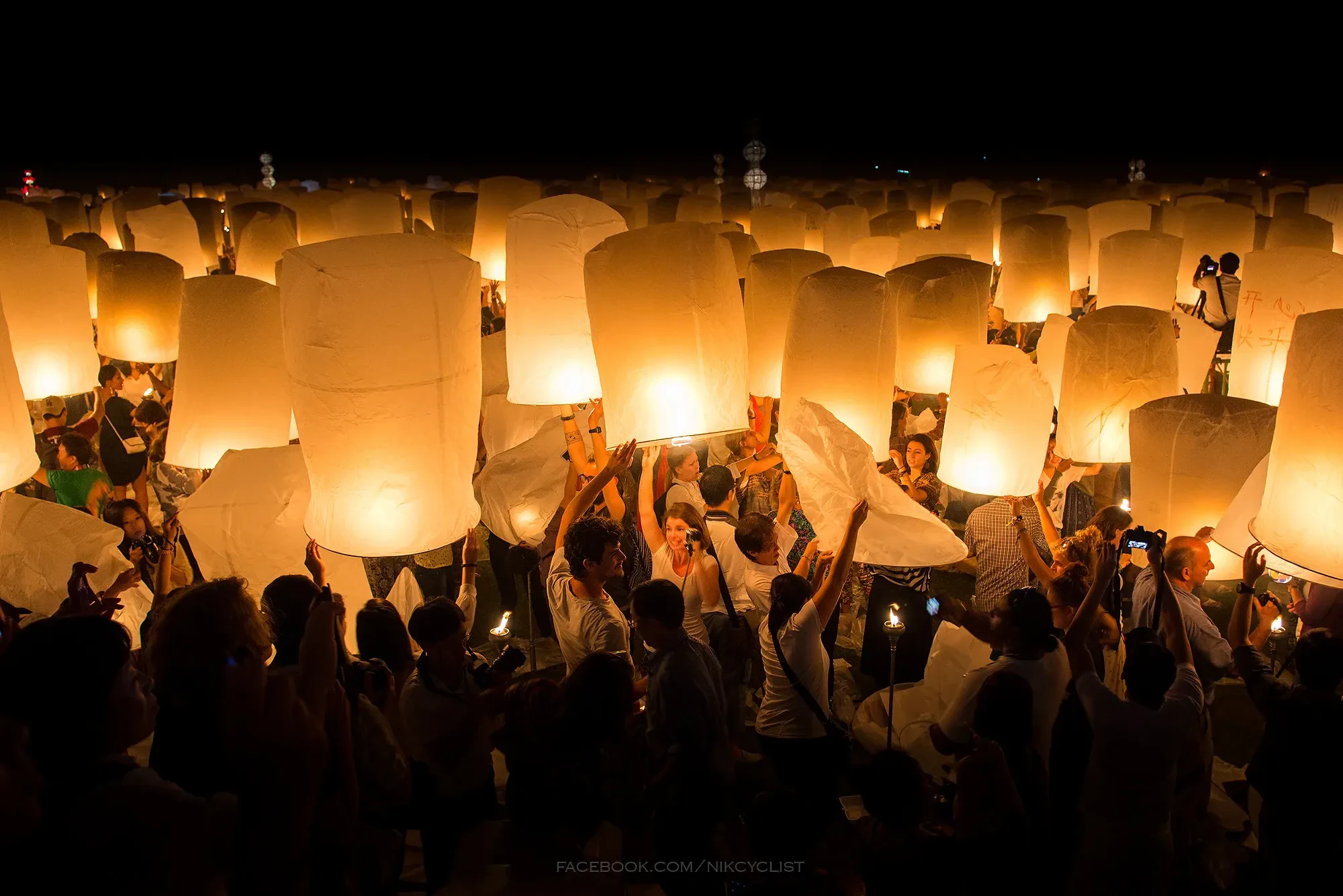 People preparing to launch sky lanterns at night during Yi Peng in Chiang Mai
