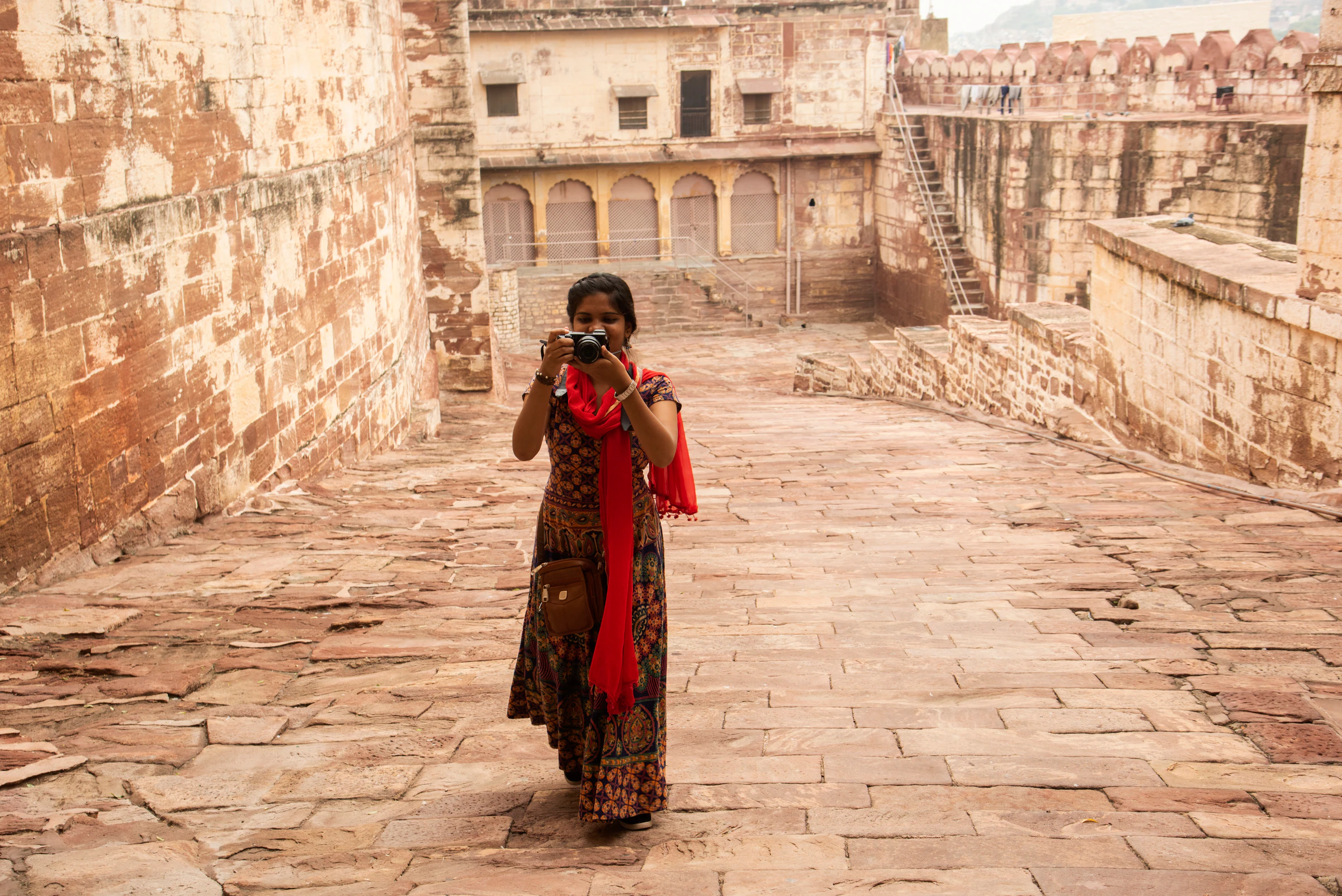 A woman with a camera walking through the courtyard of a fort in Jodhpur, India