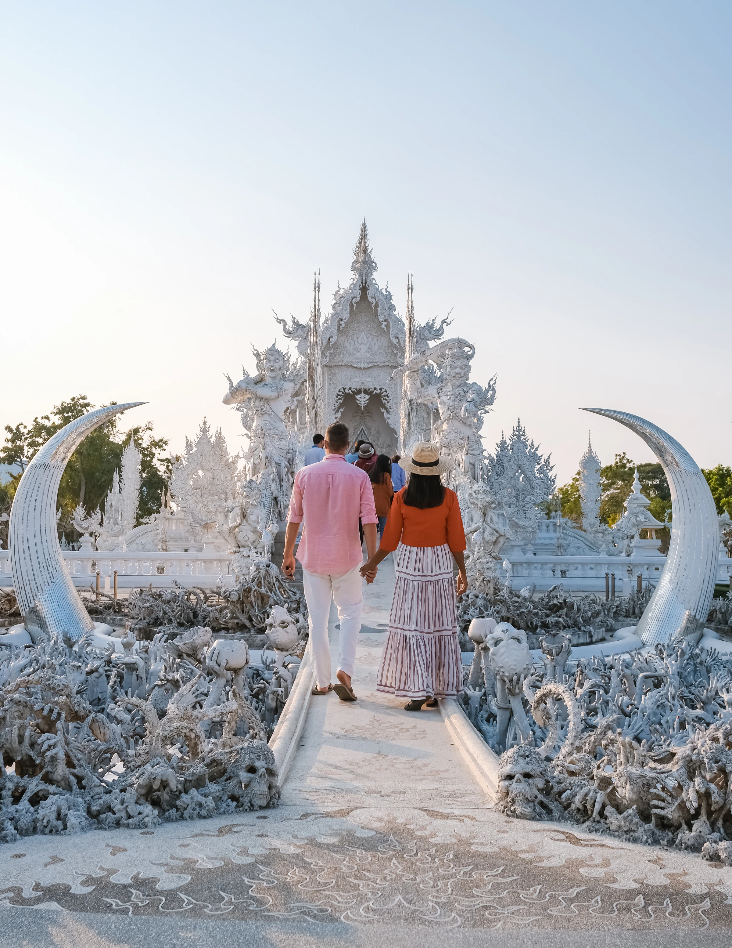 A couple walking hand in hand across the bridge to the White Temple in Chiang Rai, Thailand