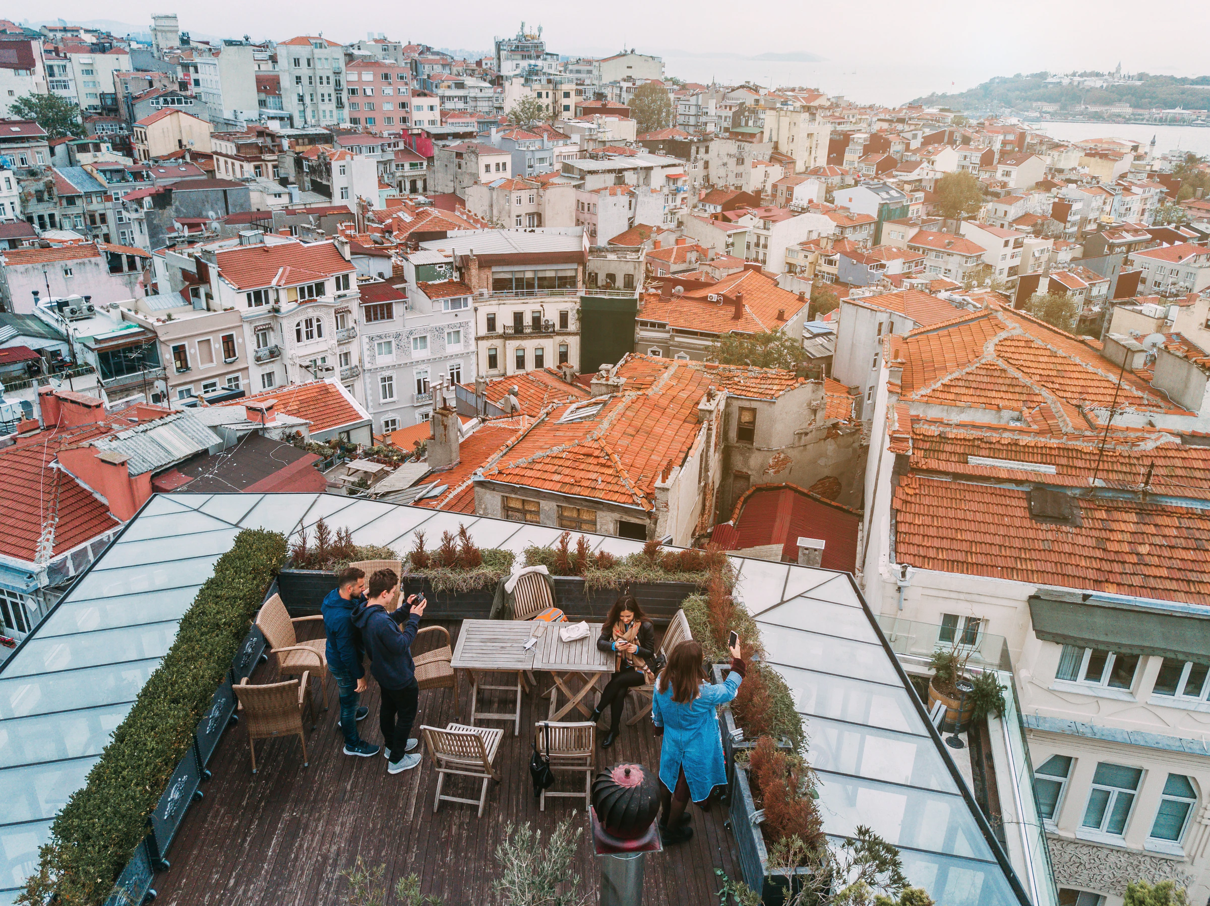 Friends sitting at a rooftop terrace overlooking the tiled roofs of Hoi An, Vietnam