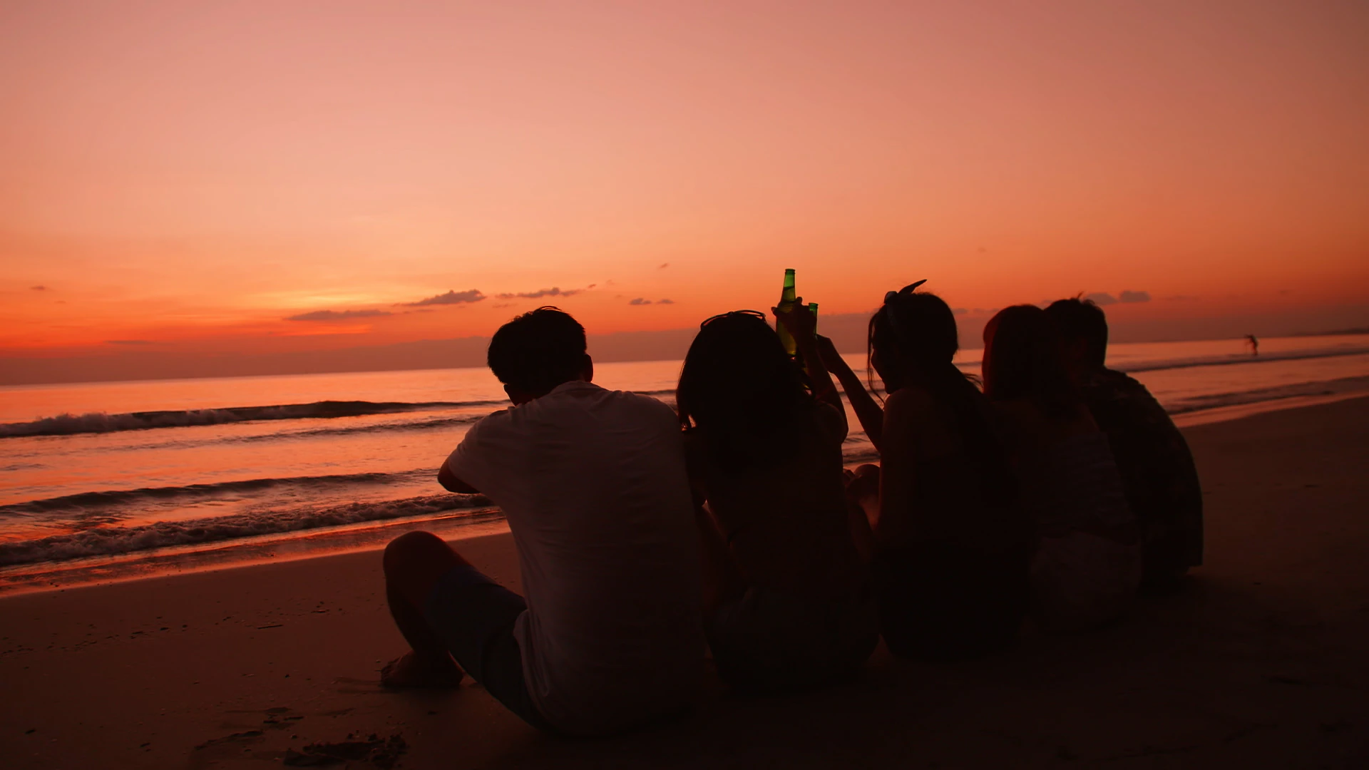 Friends sitting together on a beach watching the sunset