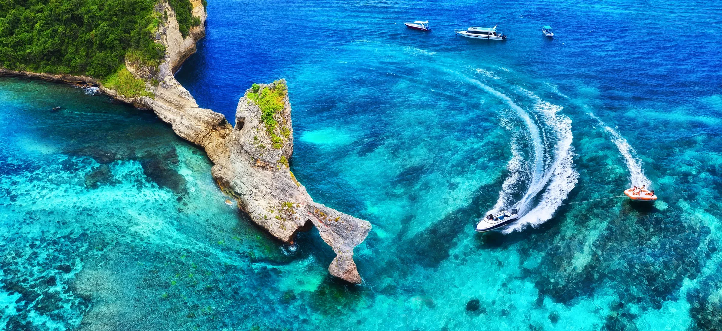 A fast boat speeding through turquoise water, leaving a white wake
