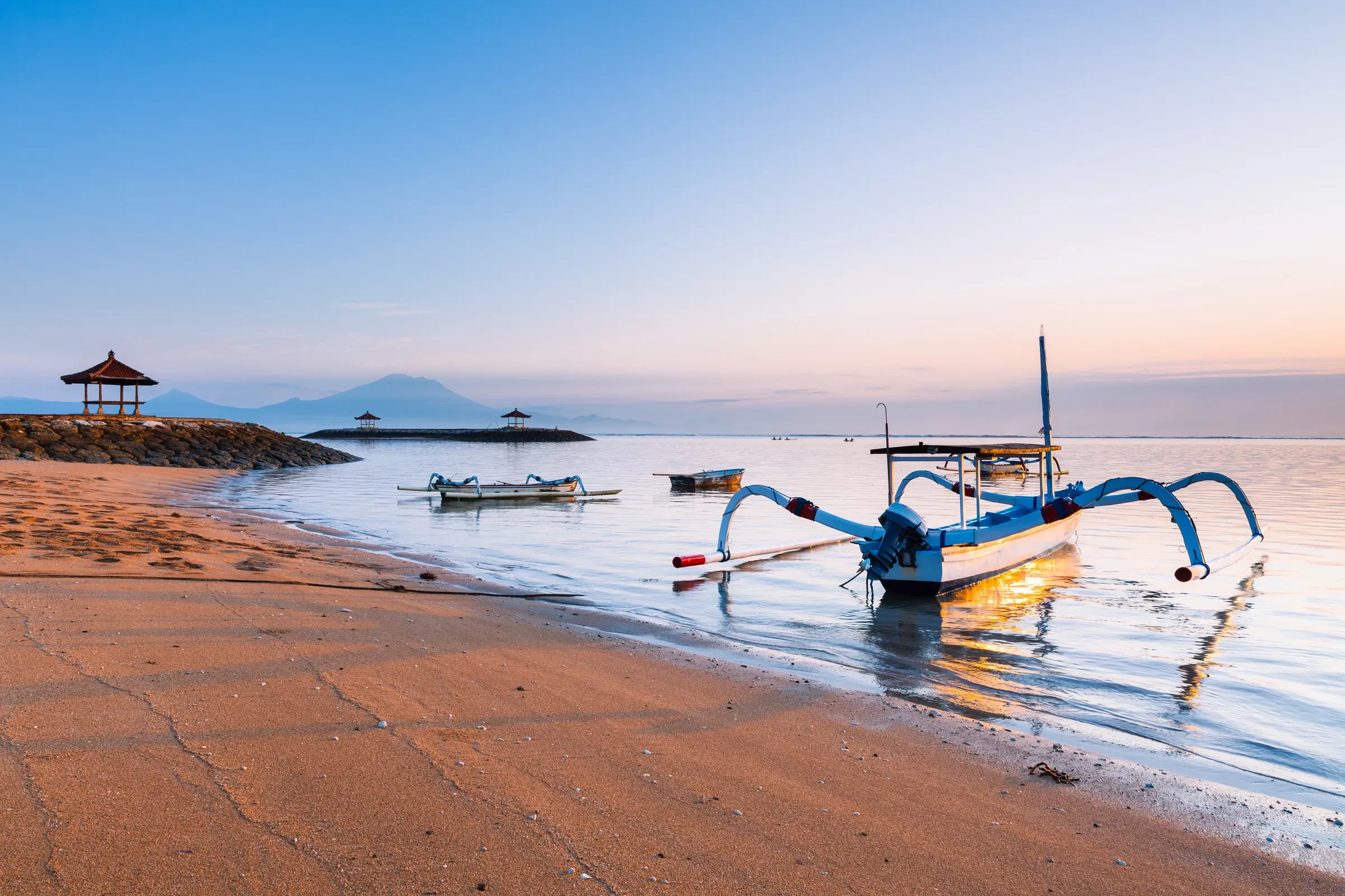 A traditional jukung boat on Sanur beach at sunrise