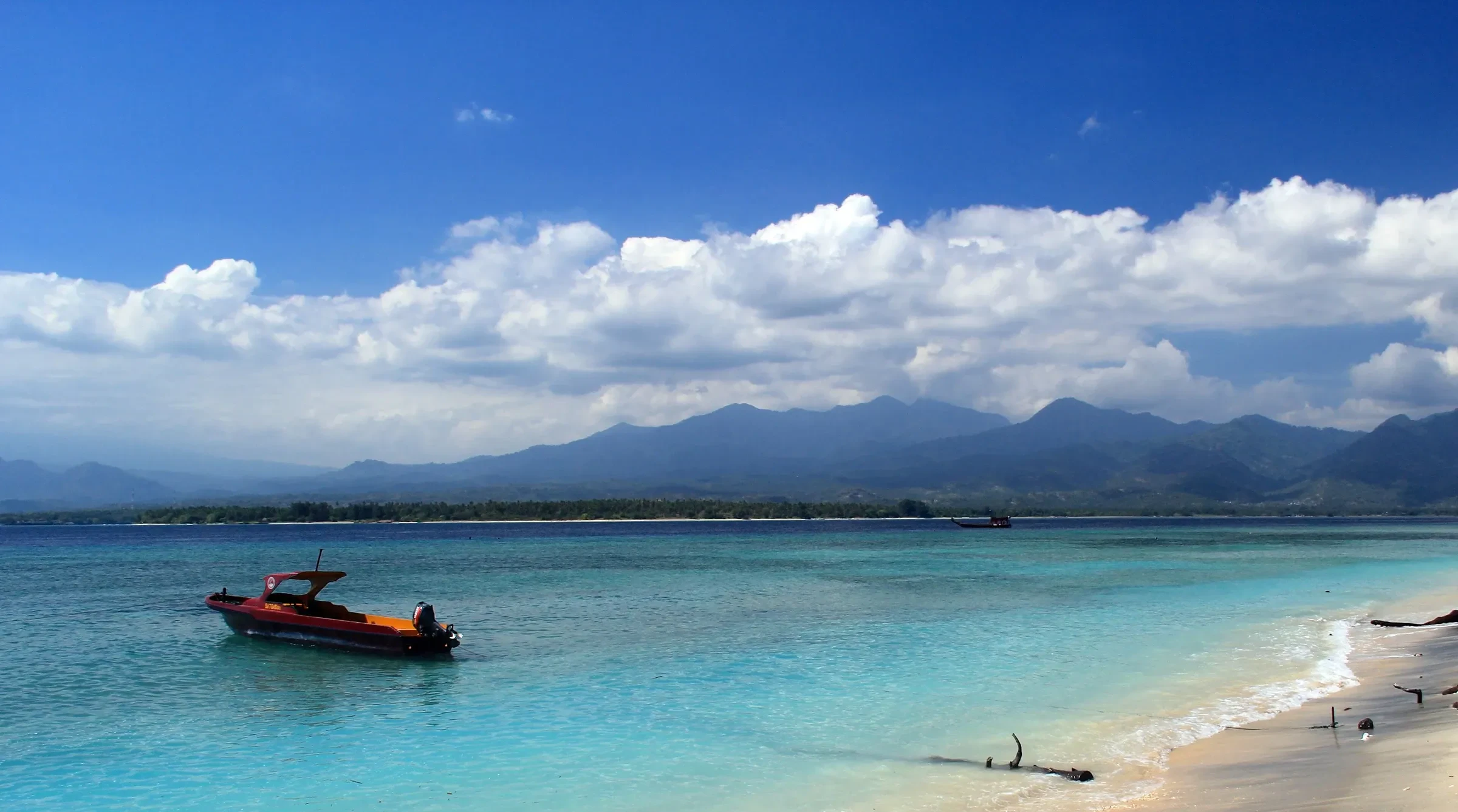 A speedboat on the turquoise water off Gili Air, with Lombok behind