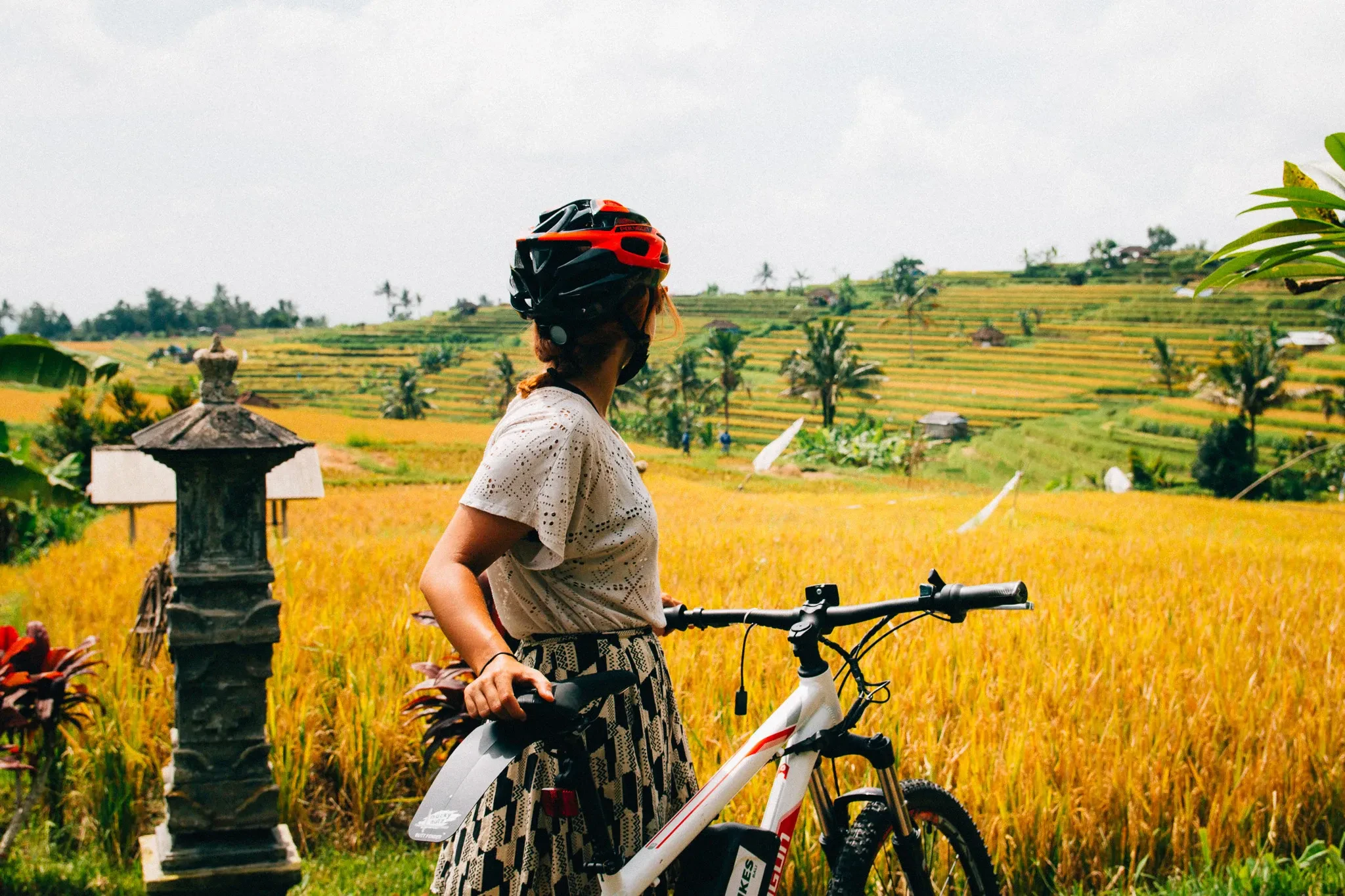 A cyclist in a helmet with a bike beside the golden rice terraces at Jatiluwih