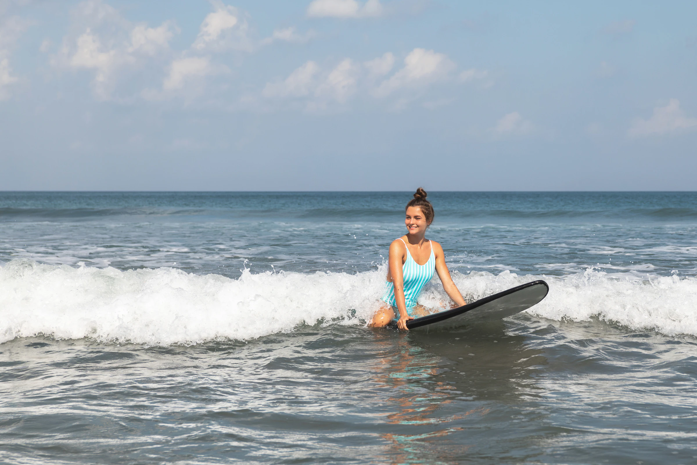 A surfer sitting on her board in the whitewash after a wave