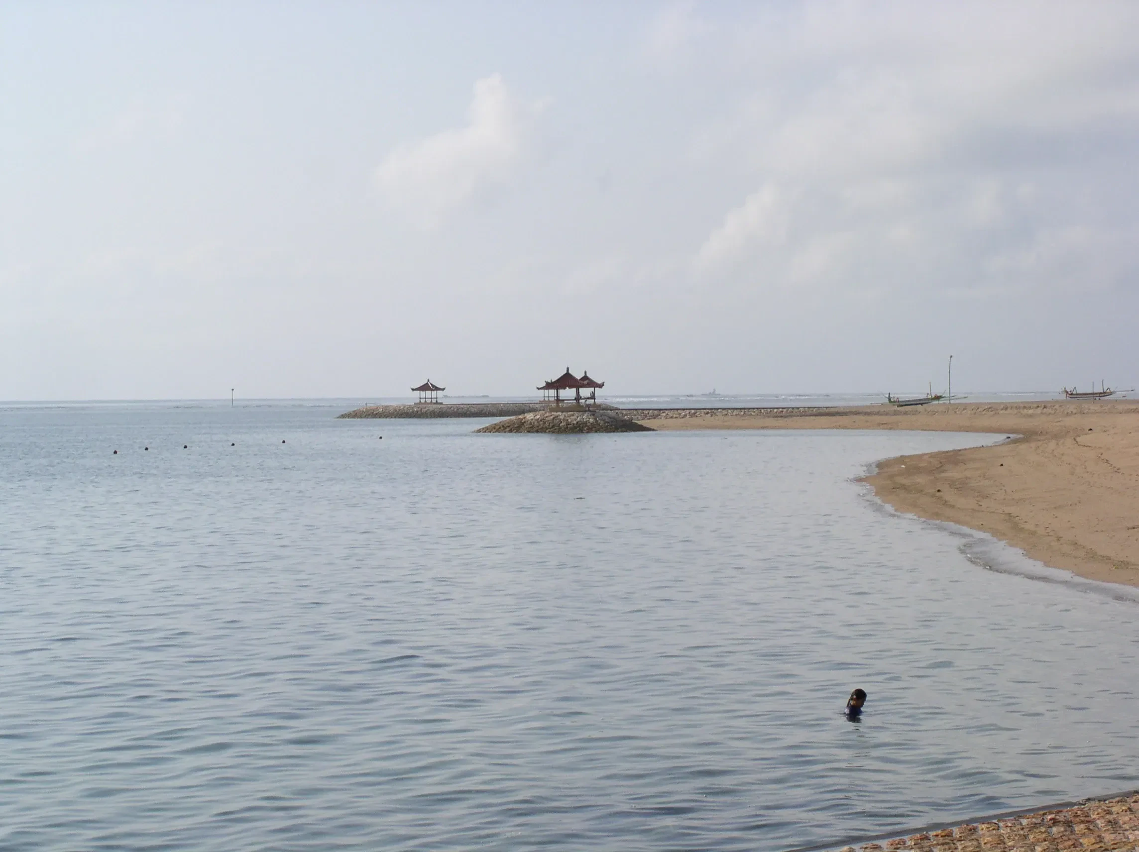 Calm shallow water and beach pavilions on a breakwater at Sanur
