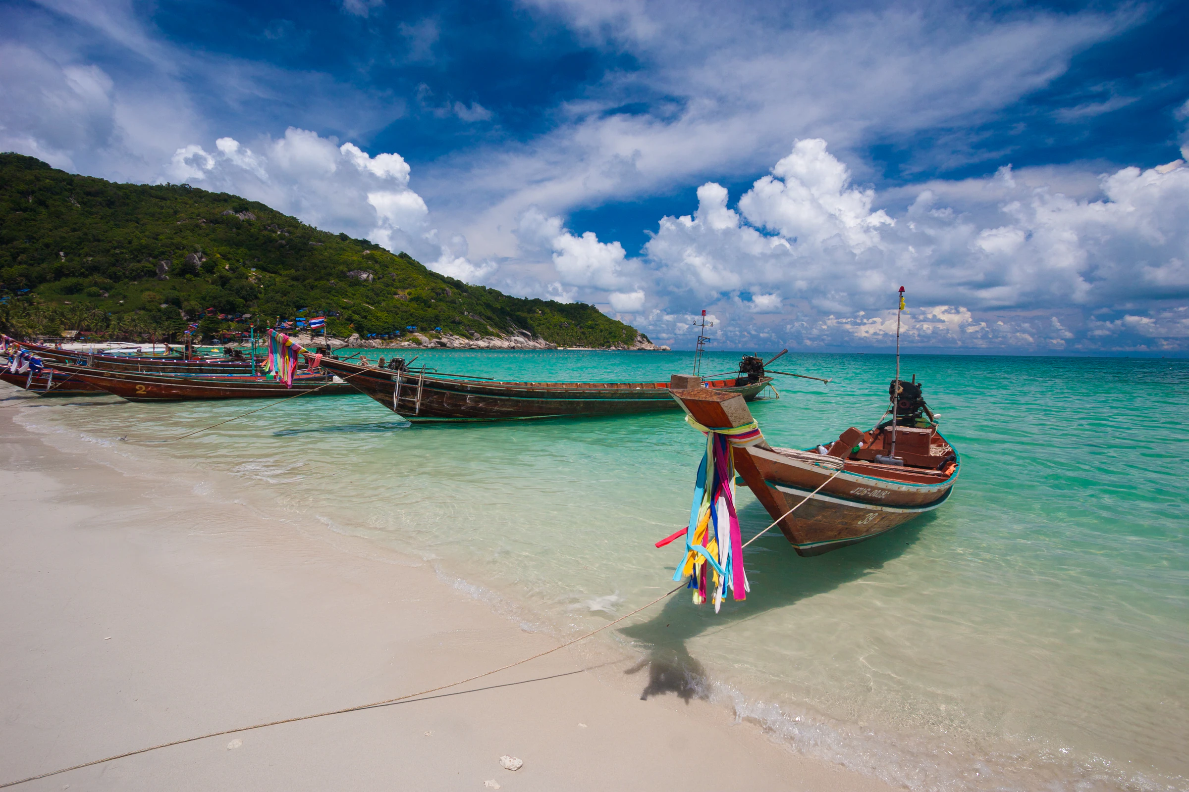 A longtail boat on a tropical beach with clear water