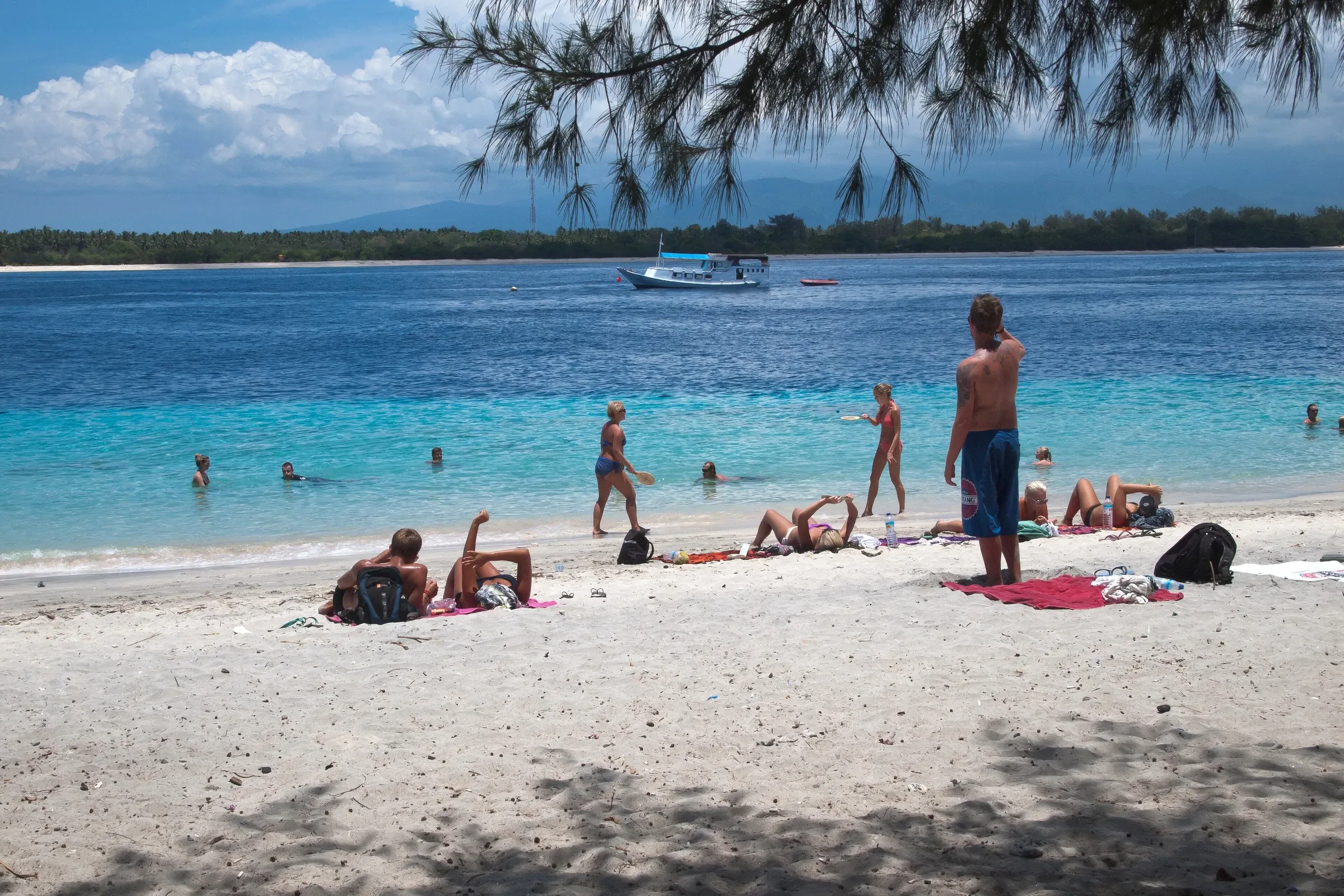 Travellers on the white-sand beach of Gili Trawangan with the Lombok coast across the water