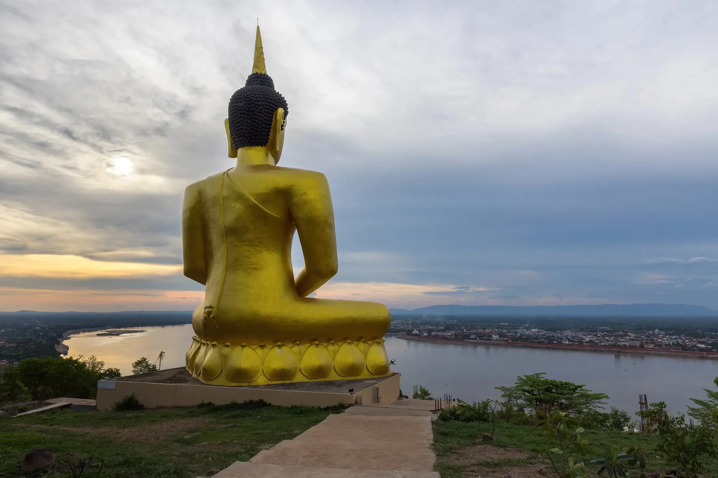 A golden seated Buddha above the Mekong at Wat Phou Salao in Pakse at sunset