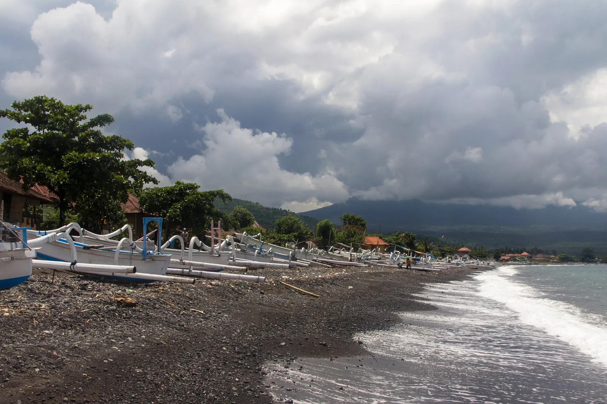 Black sand and outrigger fishing boats on the beach at Amed