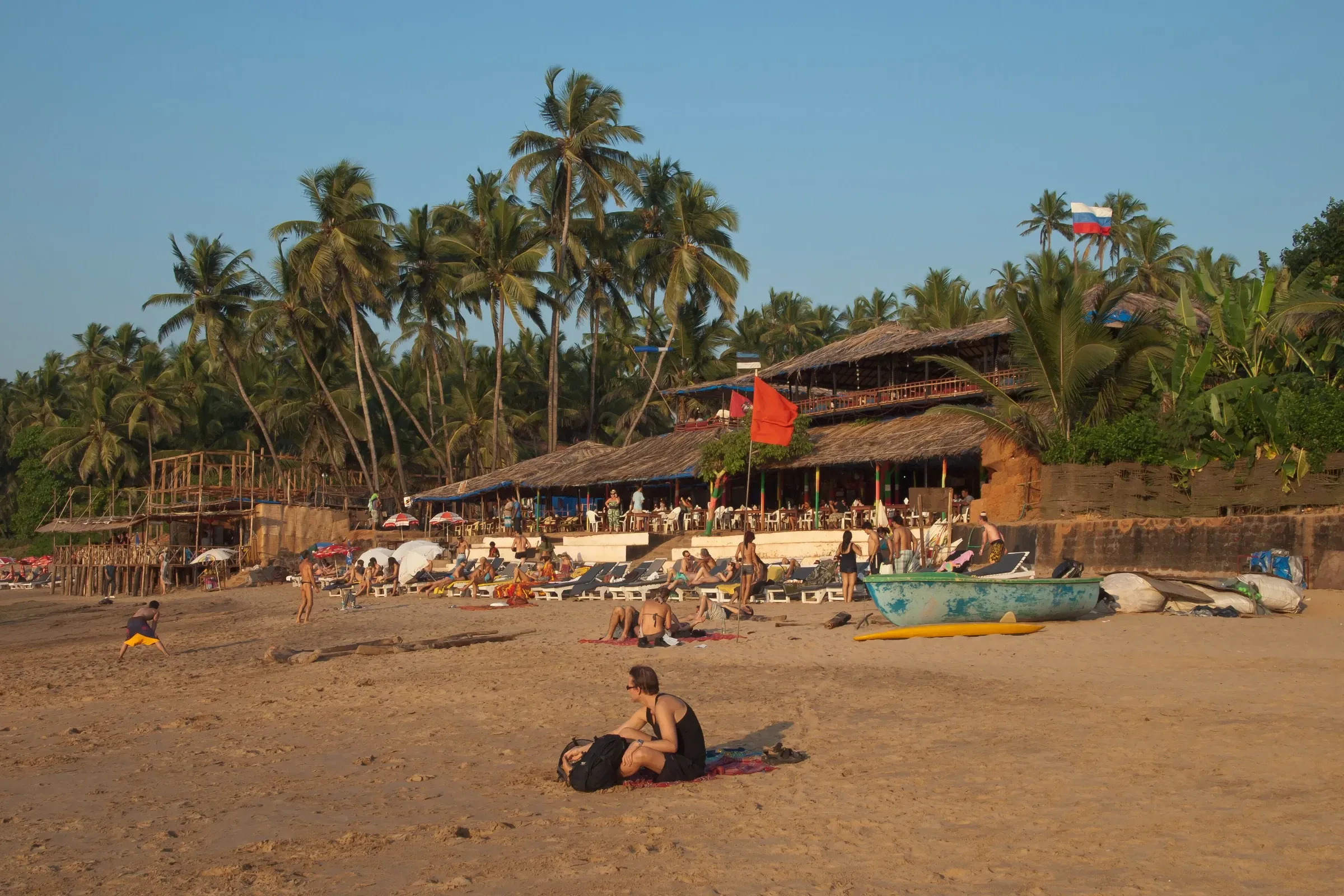 People on Anjuna beach outside a thatched beach shack in the evening