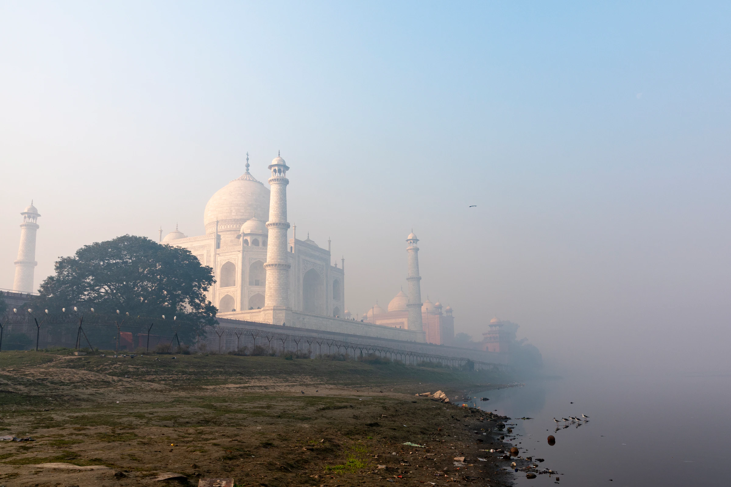 The Taj Mahal across the Yamuna River in morning mist