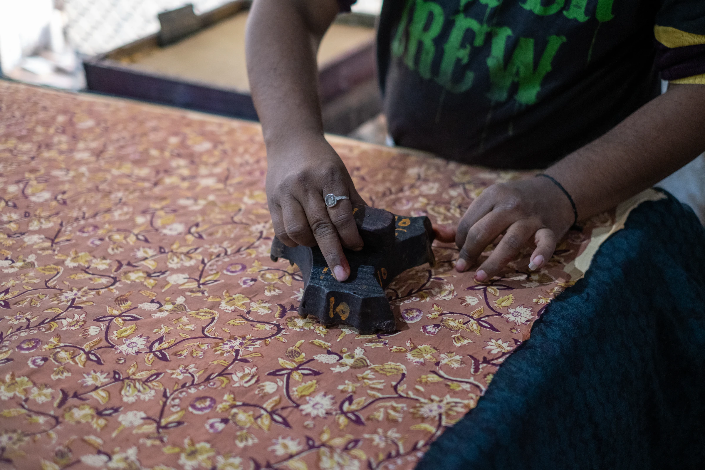 Hands printing a pattern onto cloth with a wooden block