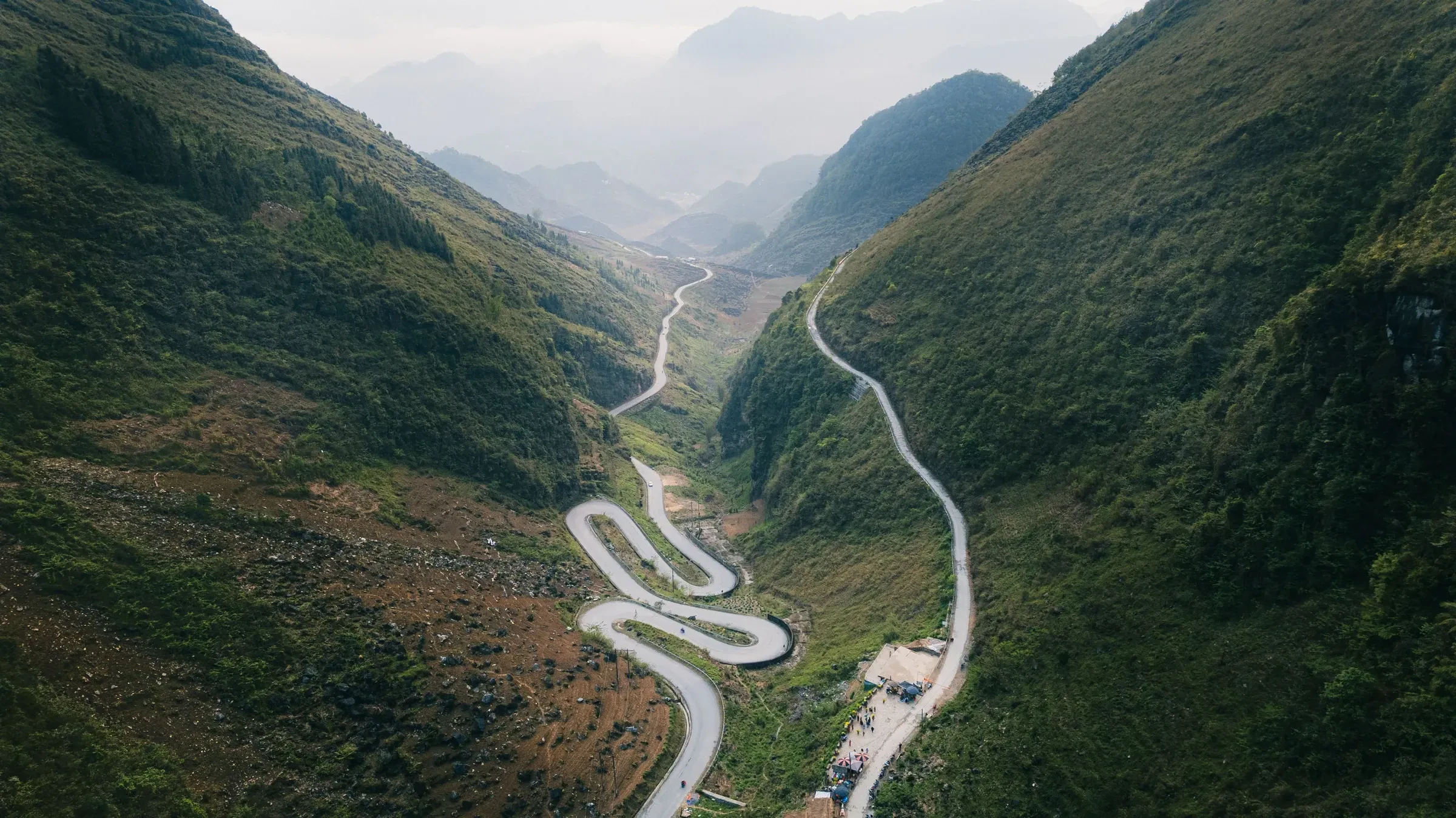 A switchback road climbing between mountains in Ha Giang