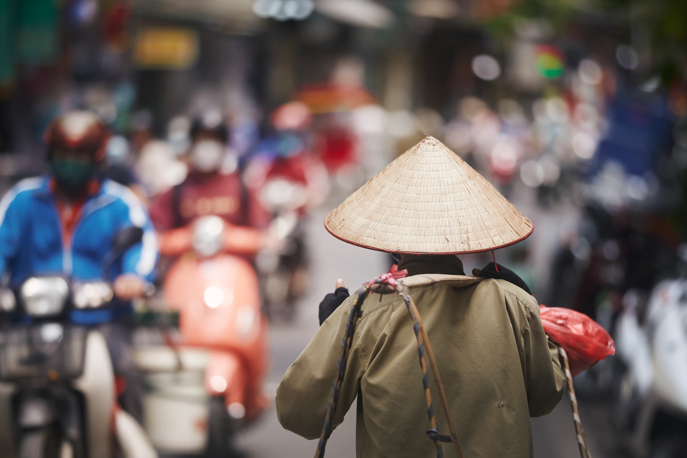 A woman in a conical hat among Hanoi scooter traffic