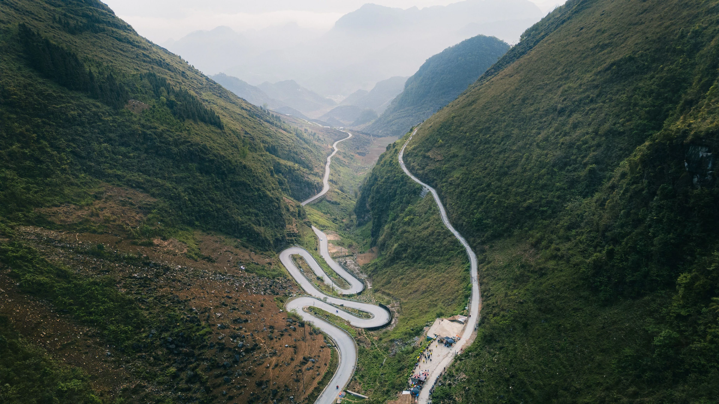 A switchback road climbing between mountains in Ha Giang