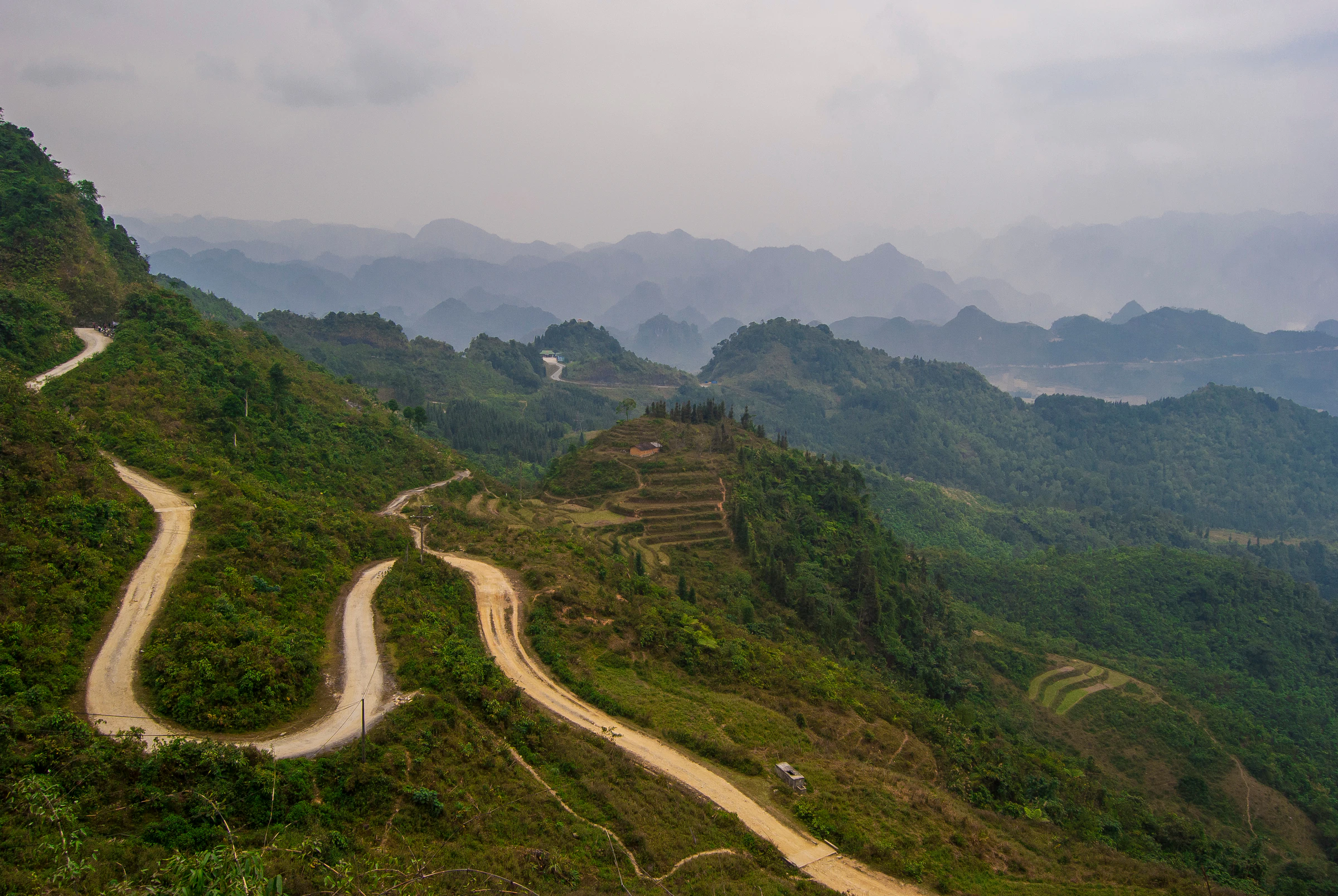 A road zigzagging down a steep valley in Ha Giang