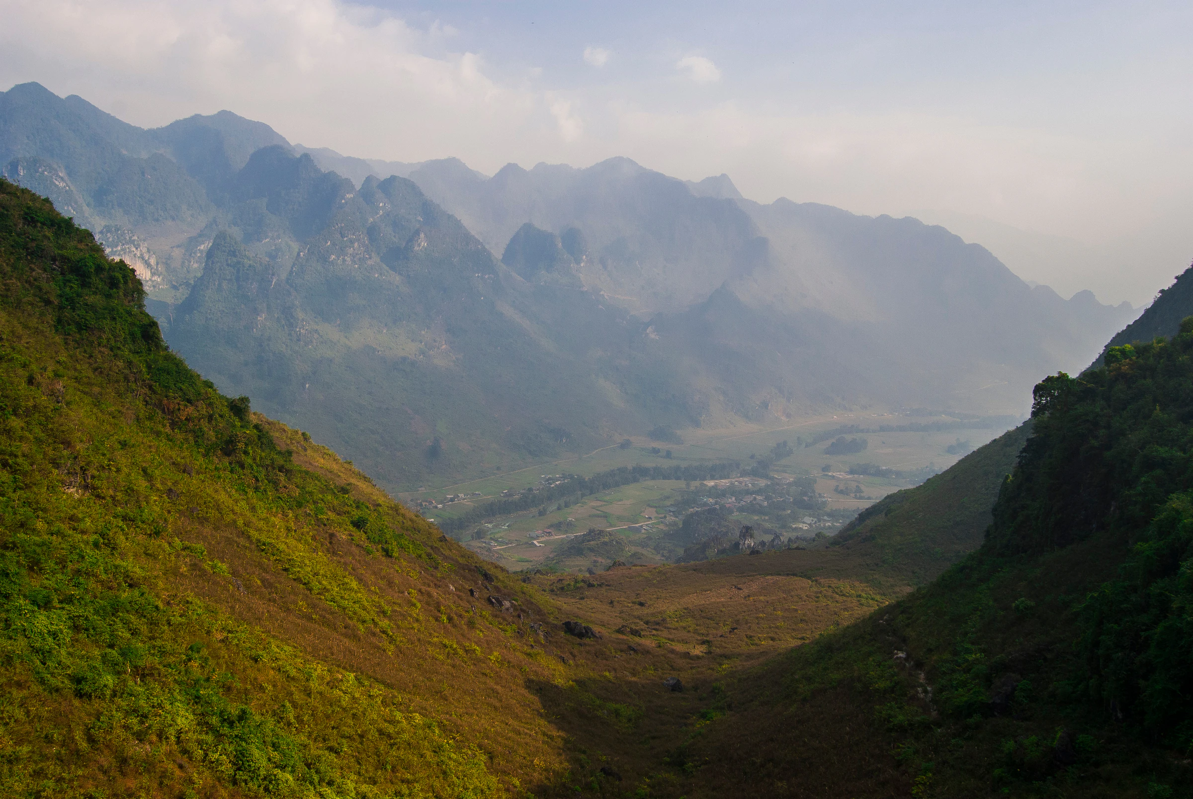 Limestone mountains and a deep valley in Ha Giang under a hazy sky